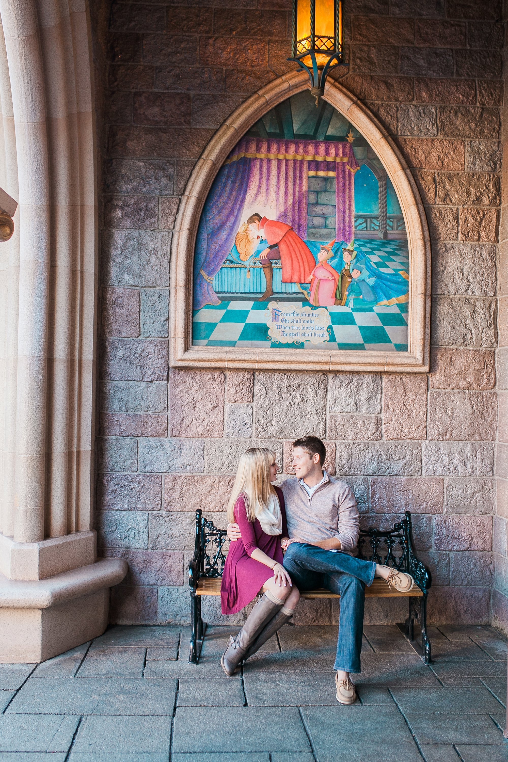  engaged couple sitting on a bench under a sleeping beauty mural 