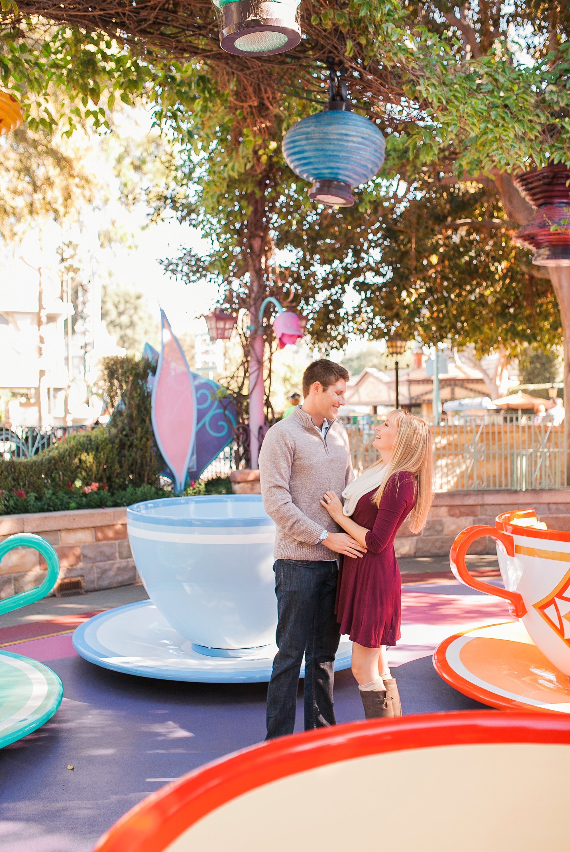  engaged couple standing in front of the teacups together 