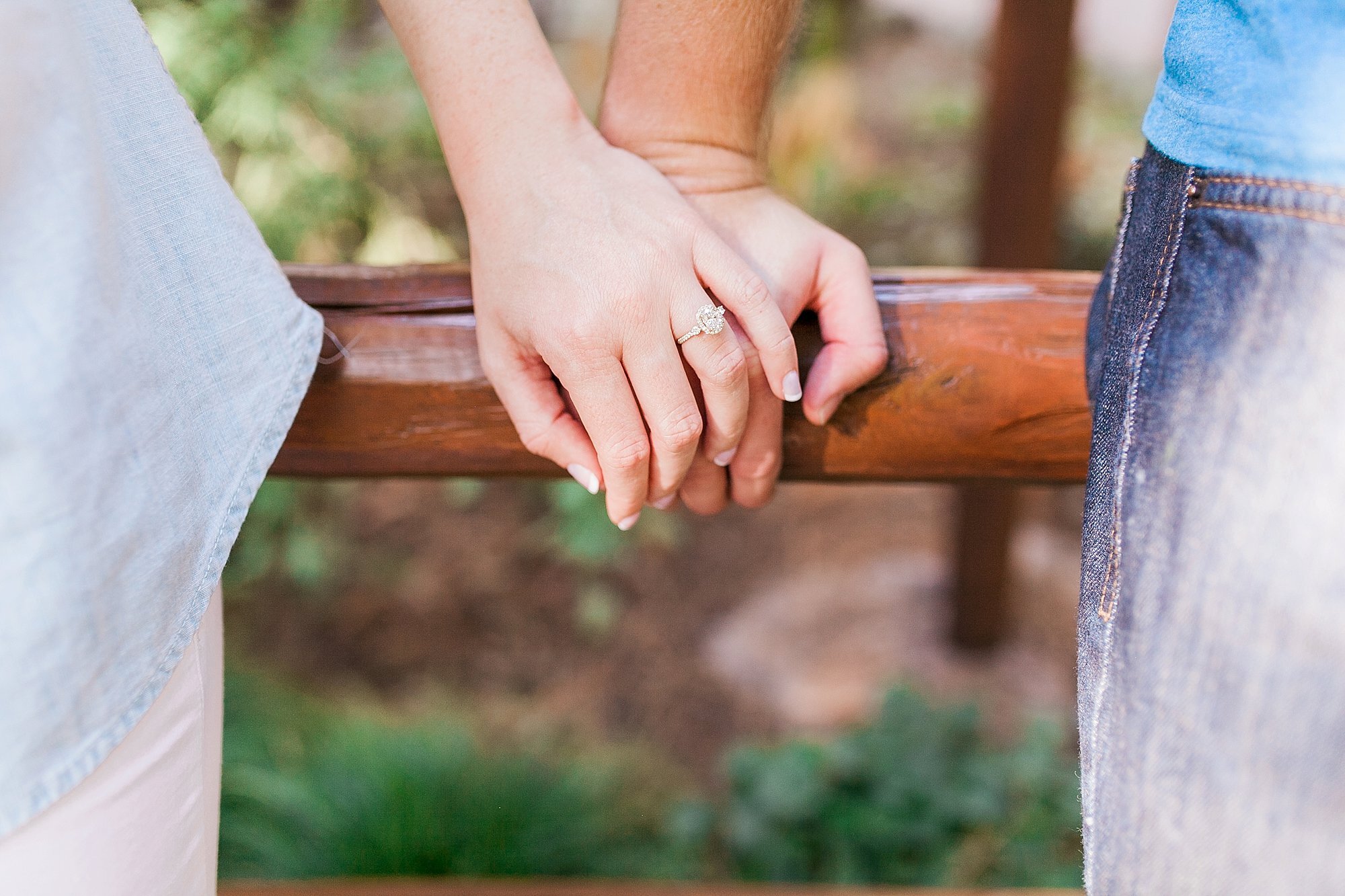  couple with engagement ring close up on railing 