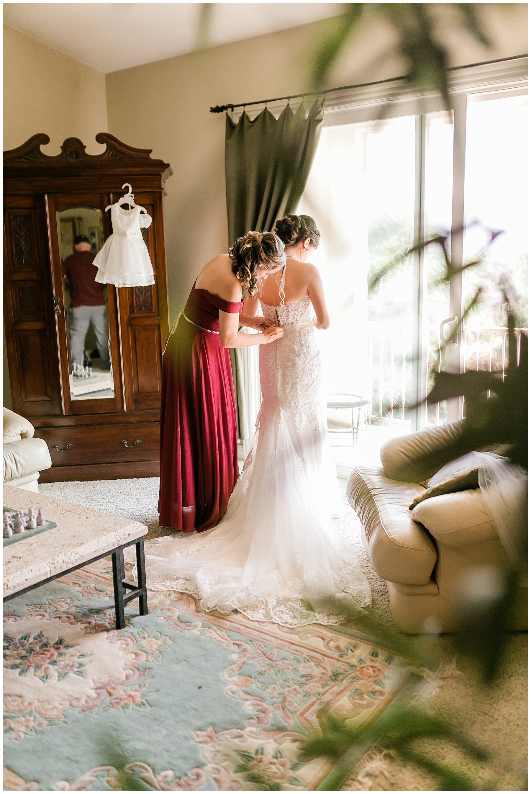 maid of honor helping bride get into her gown 
