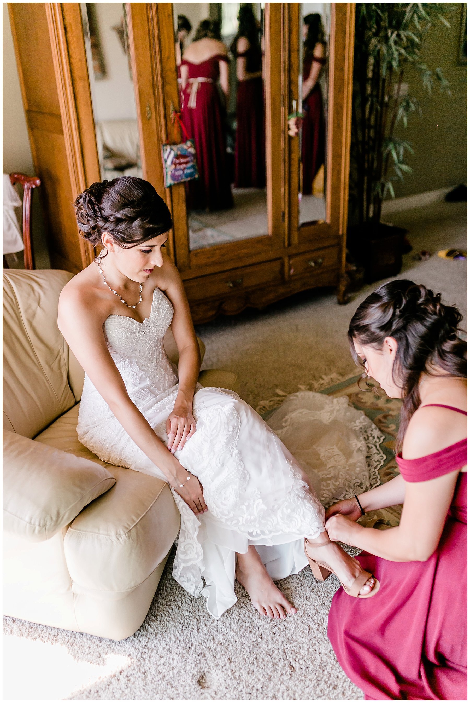  bride putting on her shoes with her maid of honor 