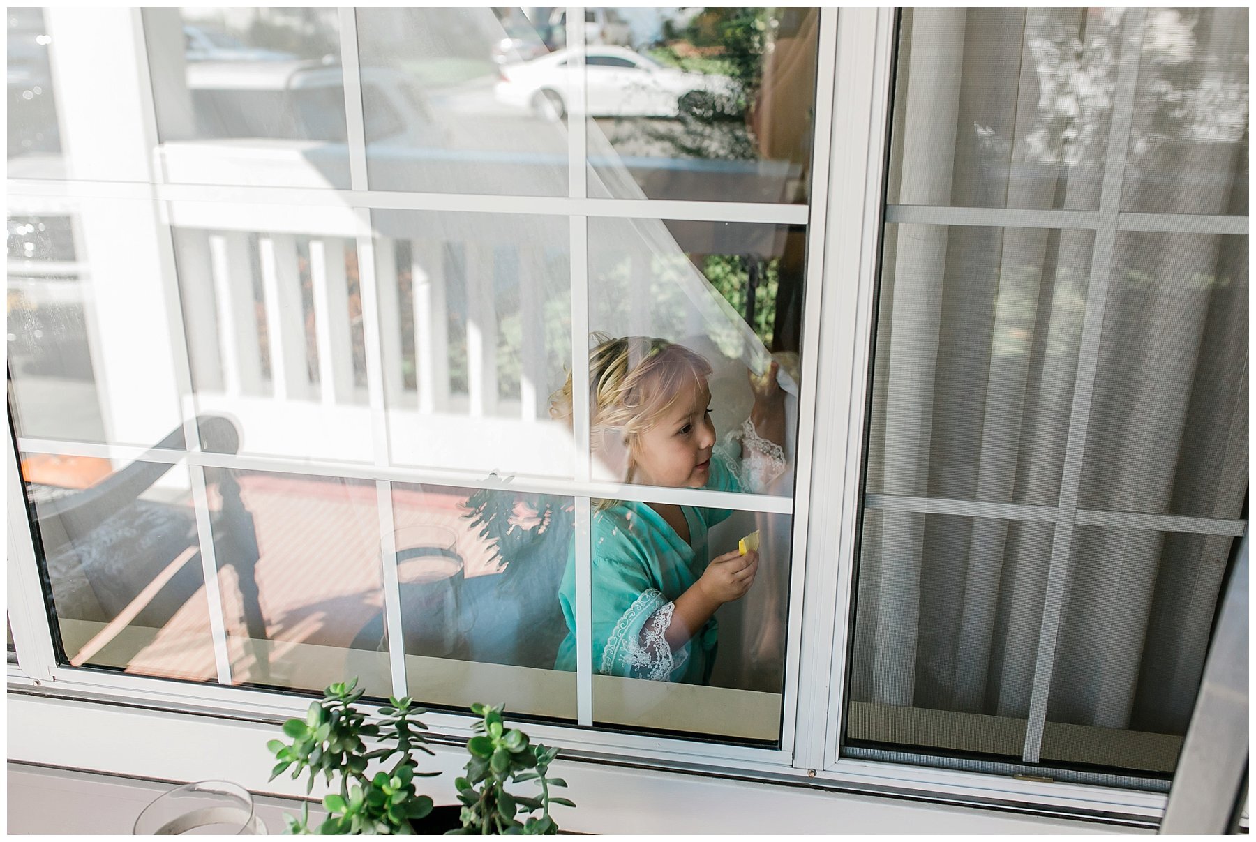  flower girl playing in the window with the white curtains 