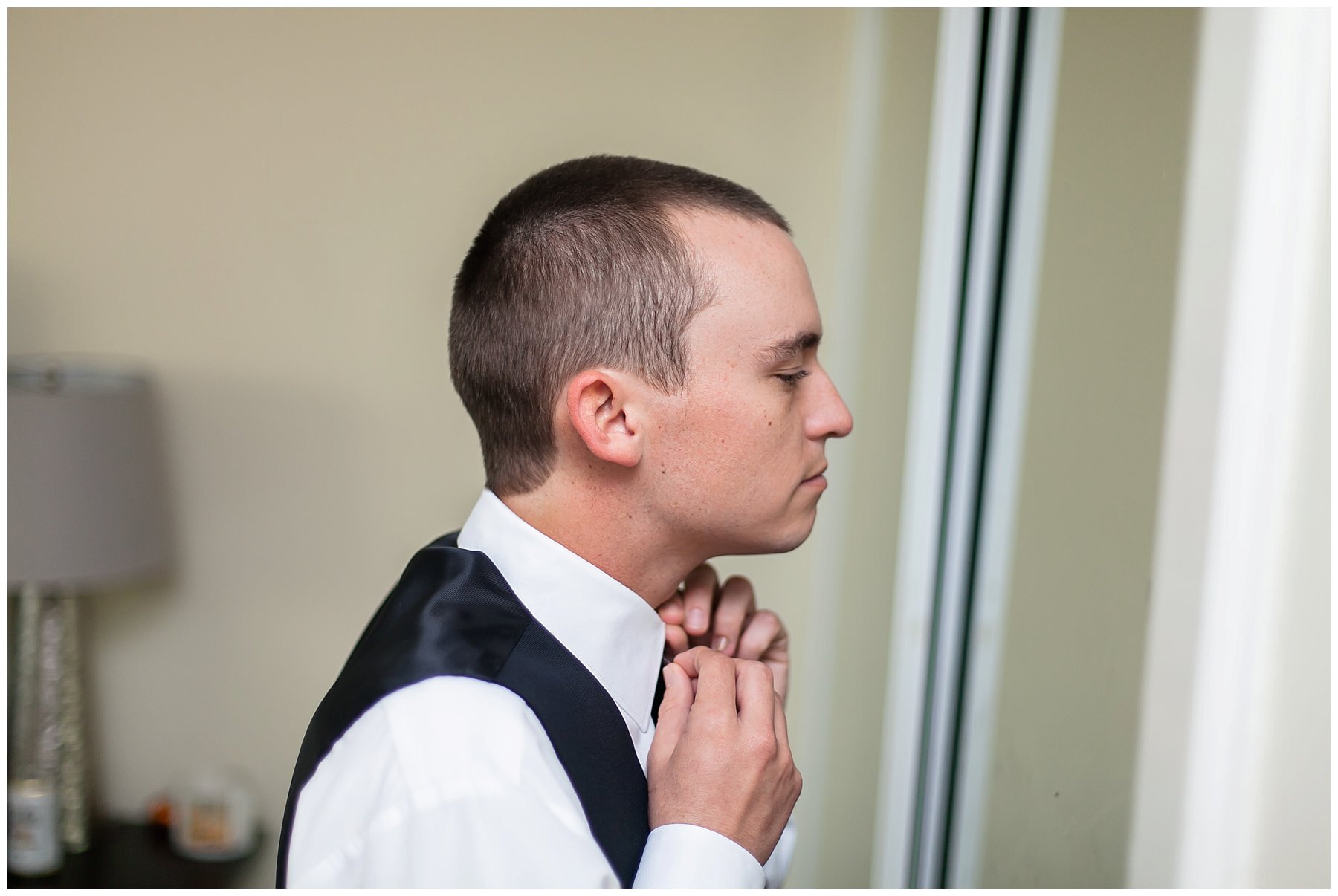  groom fixing his tie in the mirror 