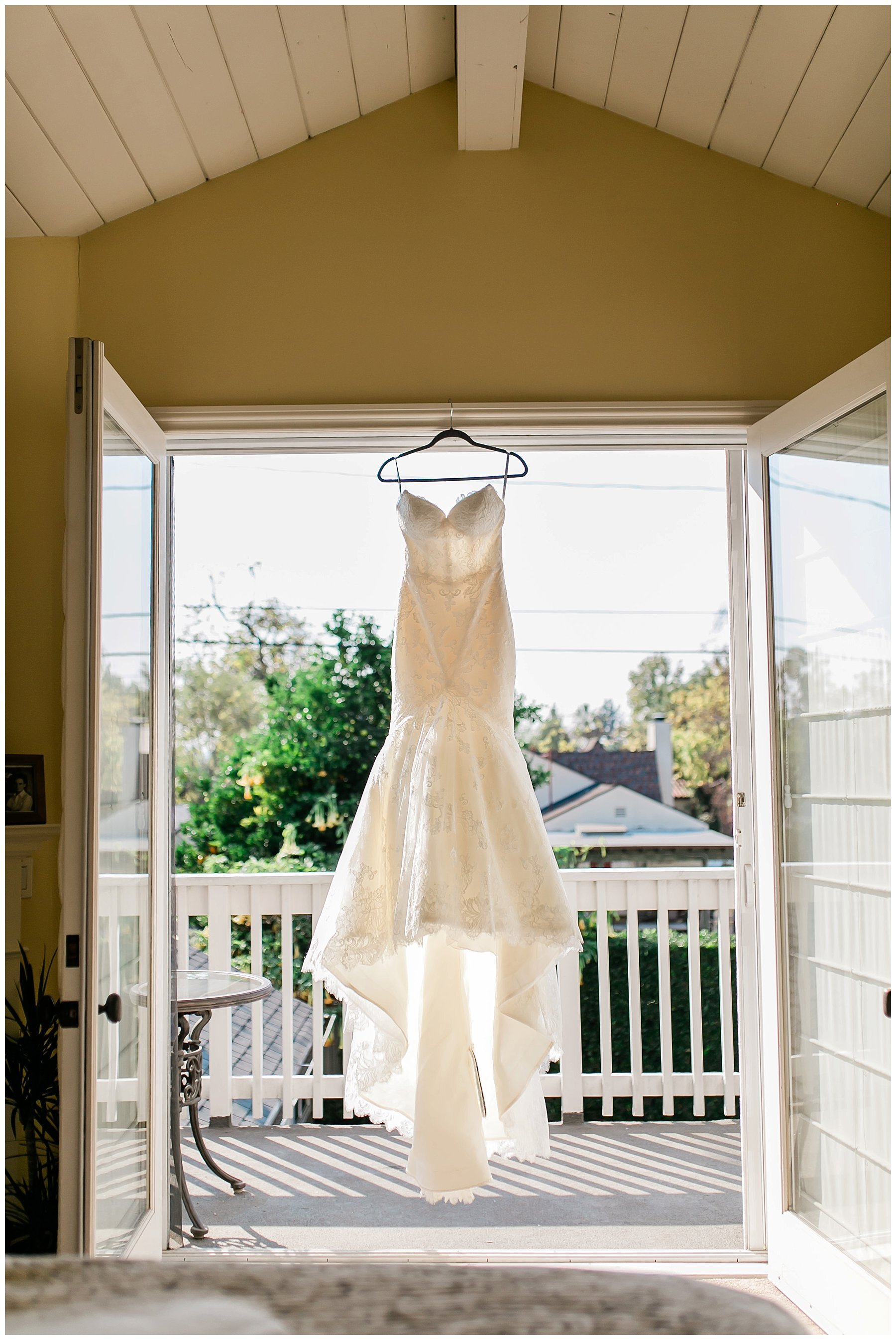  bride’s dress hanging in the doorway out to the balcony 