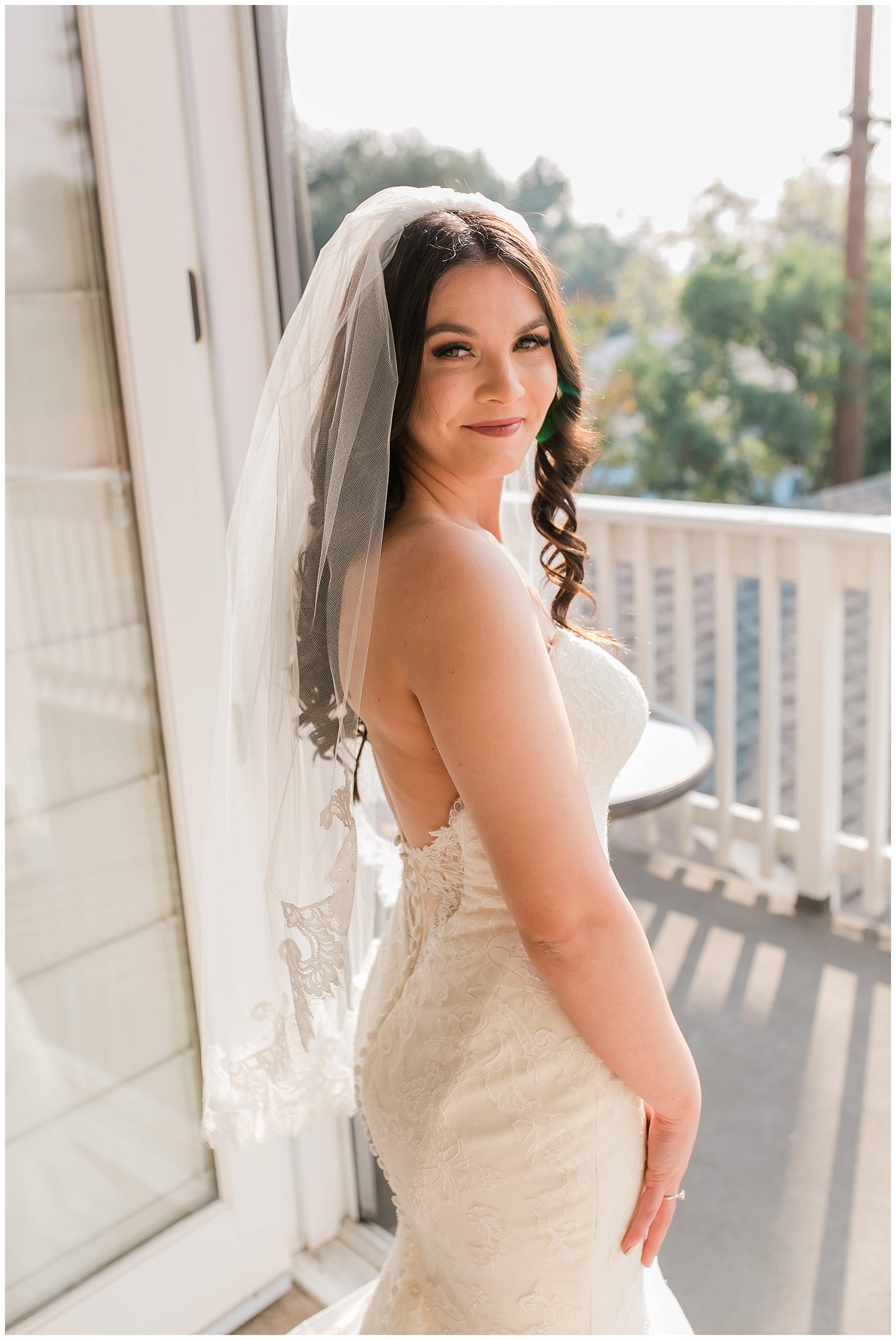  bride looks over her shoulder with her gown and veil on 