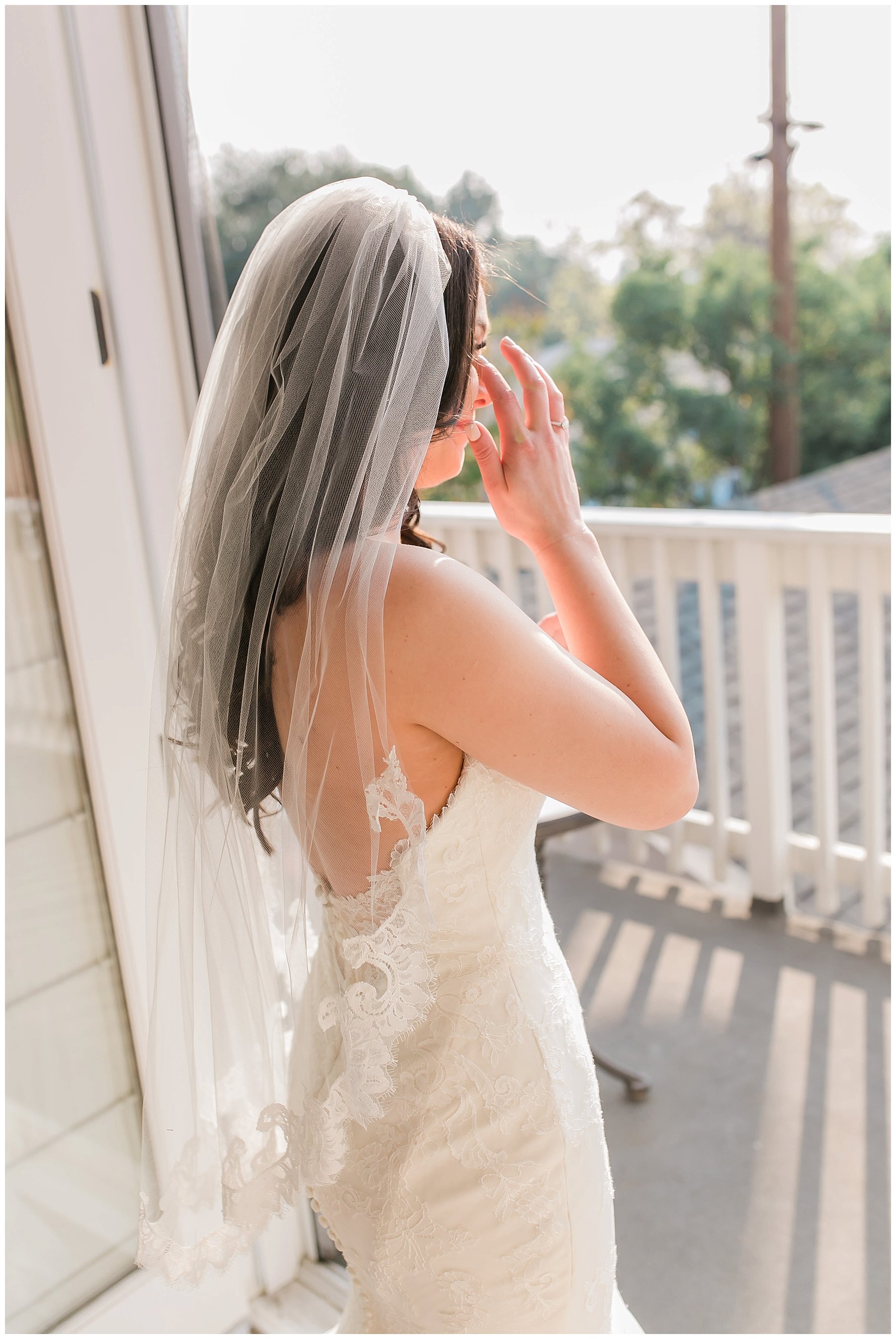 bride looks out over the balcony in her gown and veil 