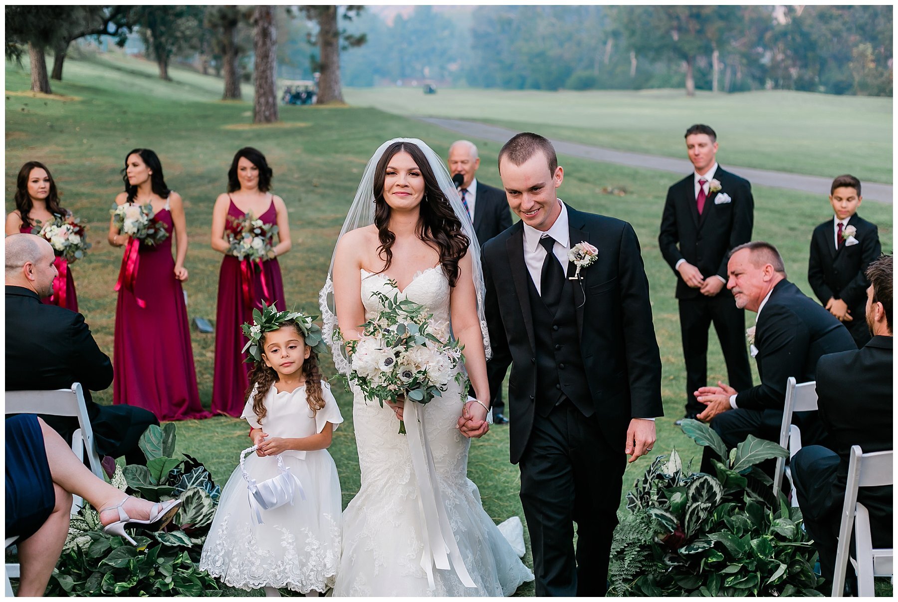  bride and groom walk down the aisle with the flower girl by their side 