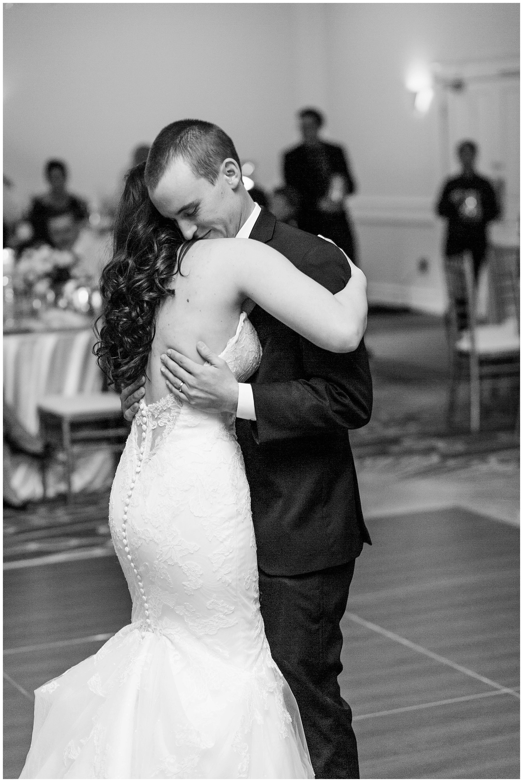  black and white photo of bride and groom dancing and embraced 