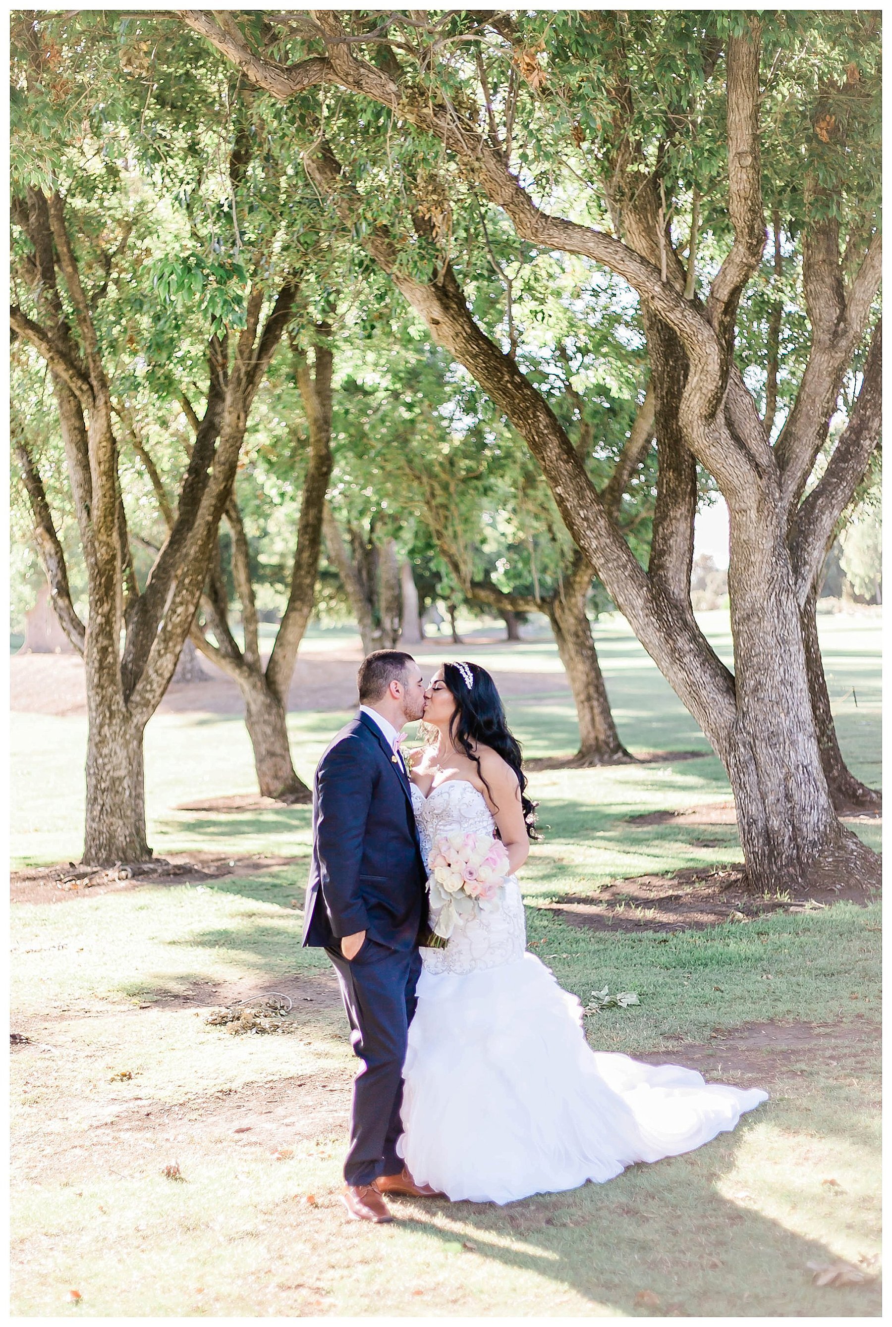  bride and groom kiss in front of the garden trees 