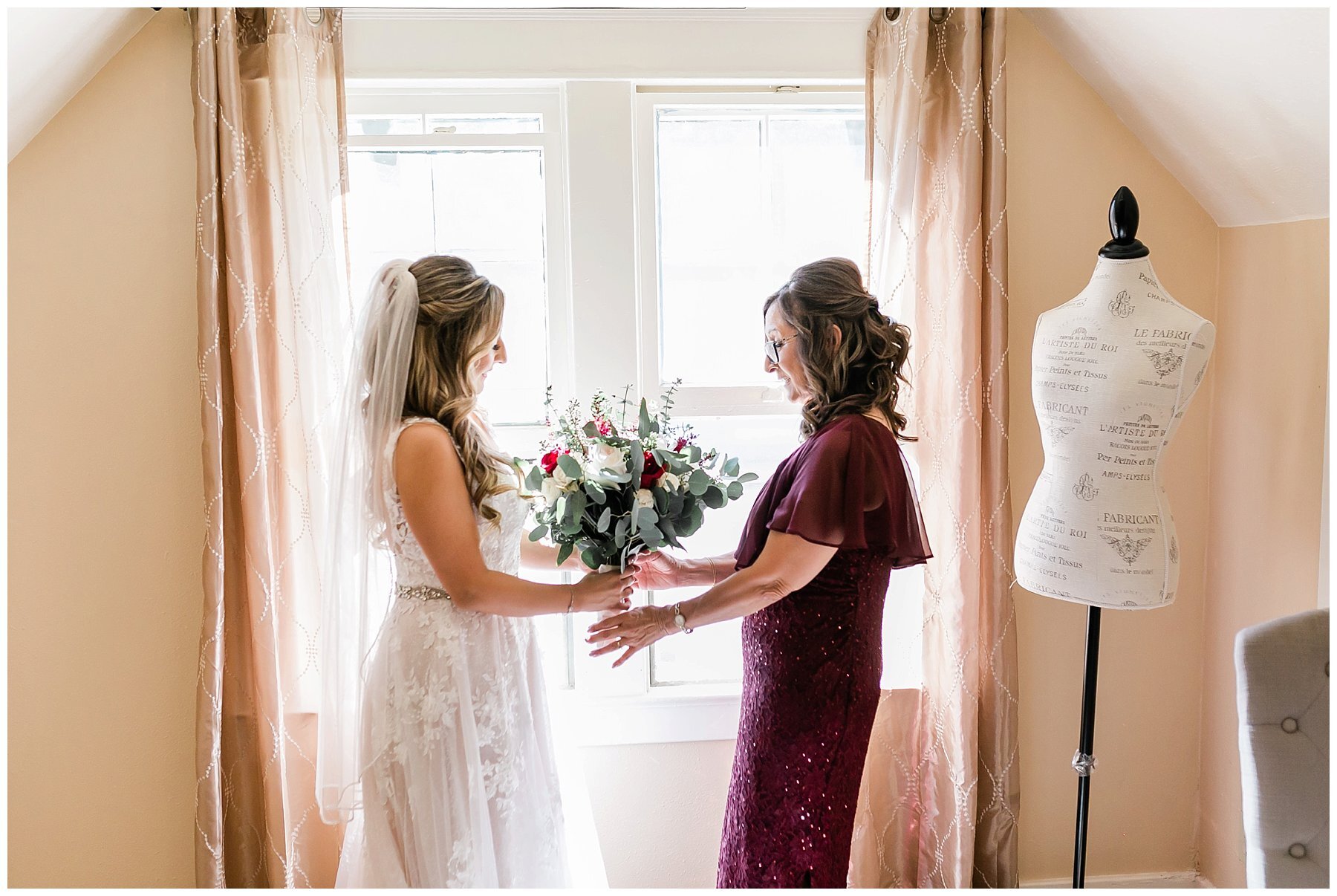  bride holding her bouquet with her mom in the light from the window 