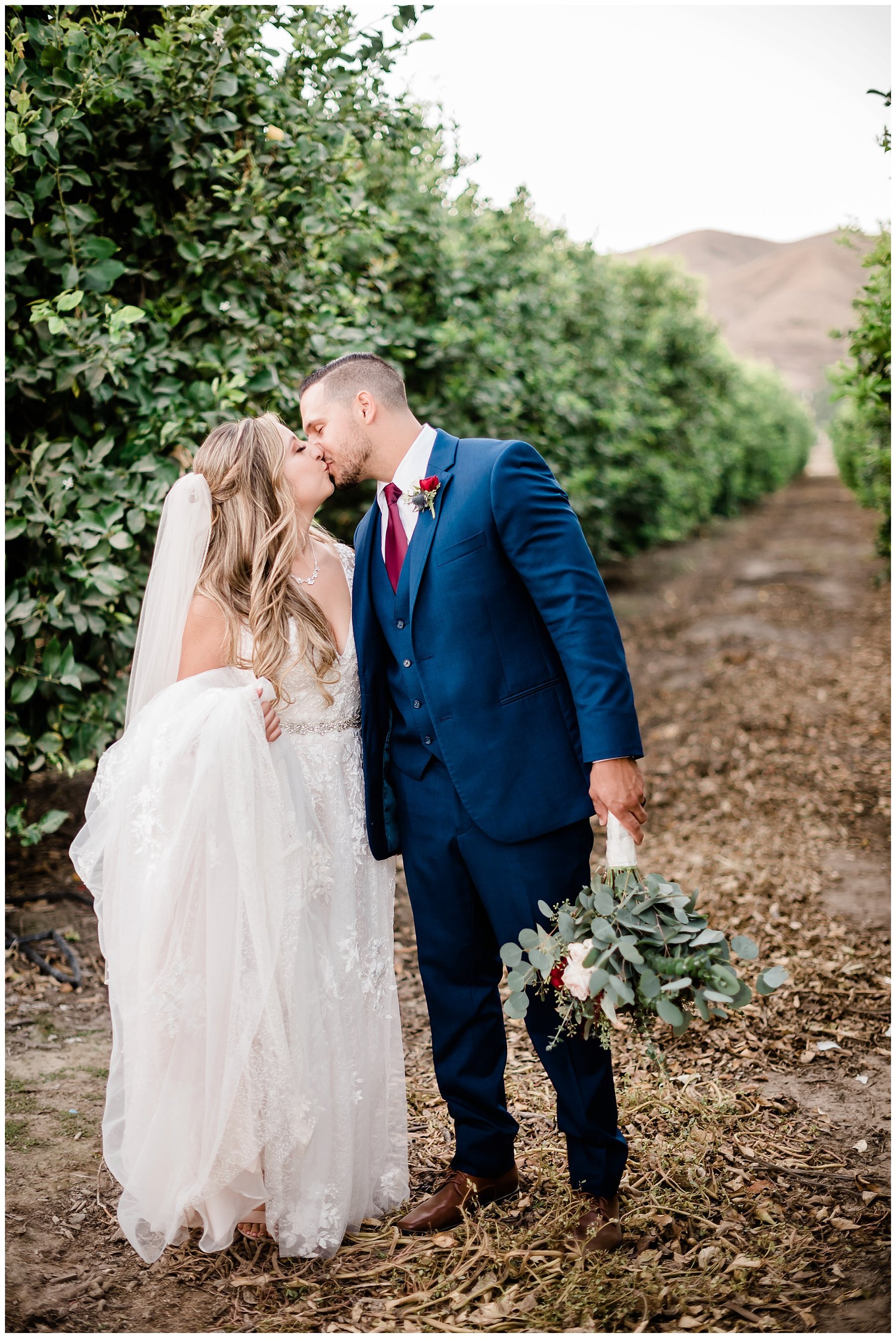  bride and groom together on a dirt path flanked by hedges 
