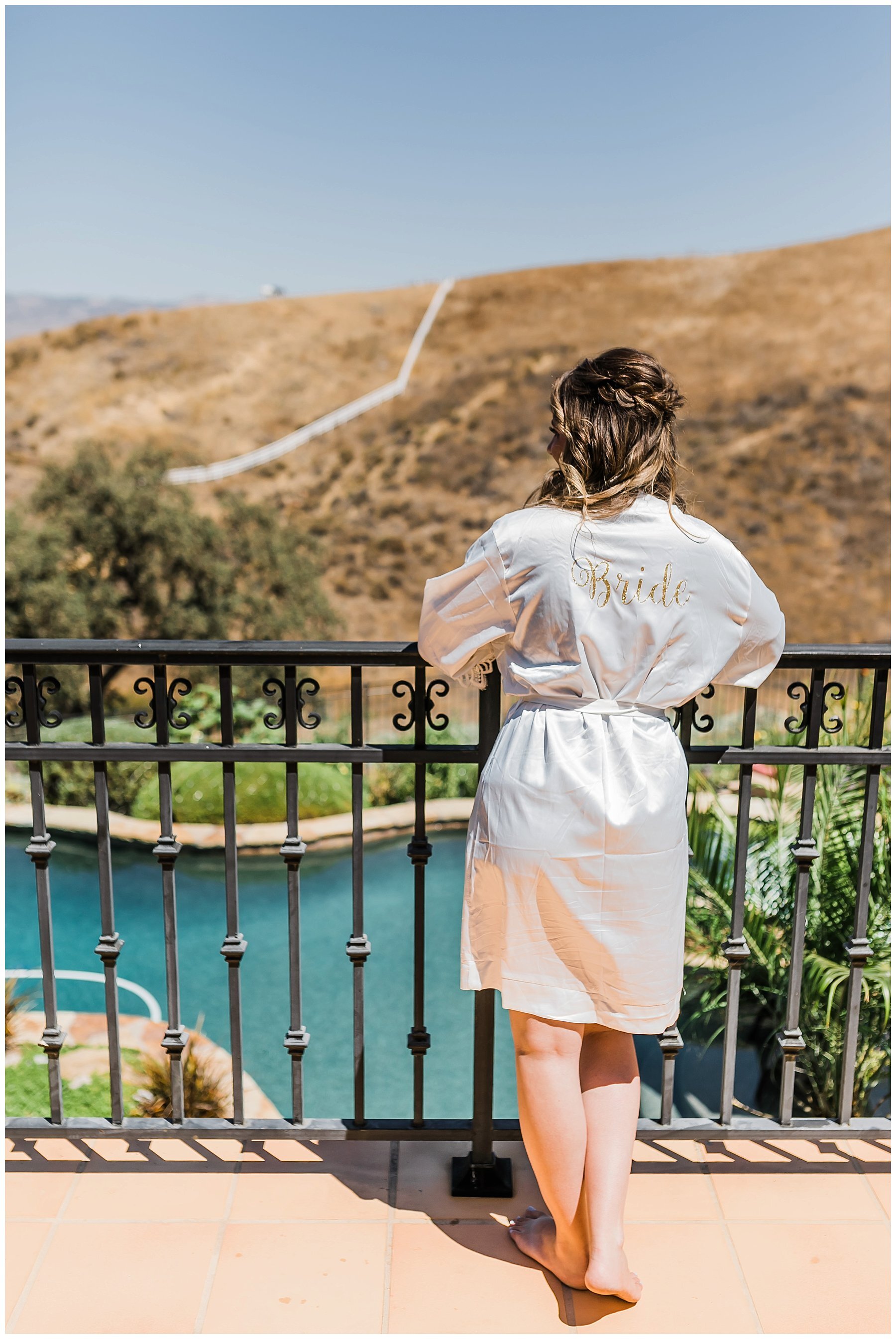  bride in her robe looking over the the background pool 