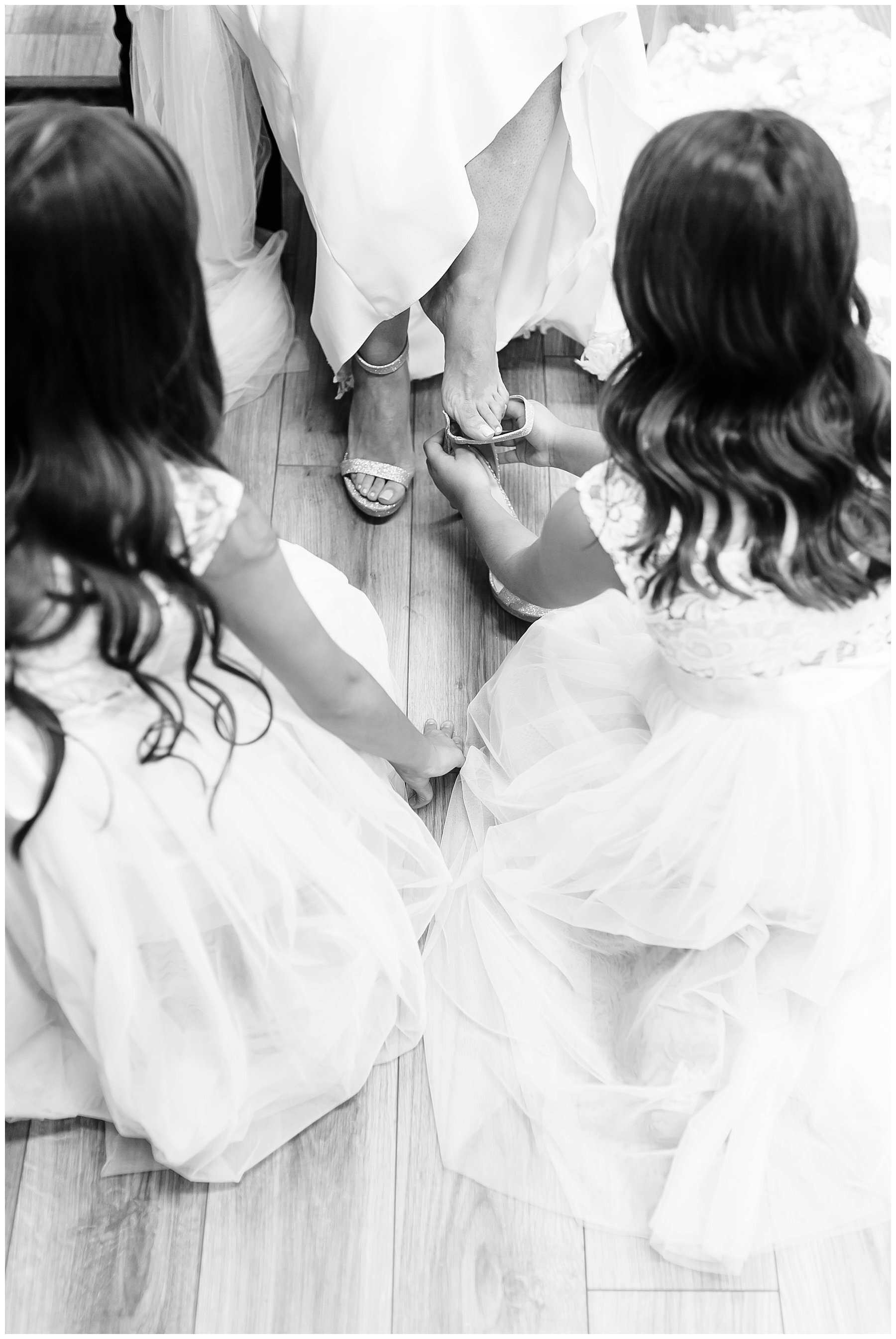  flower girls putting on bride’s heels 