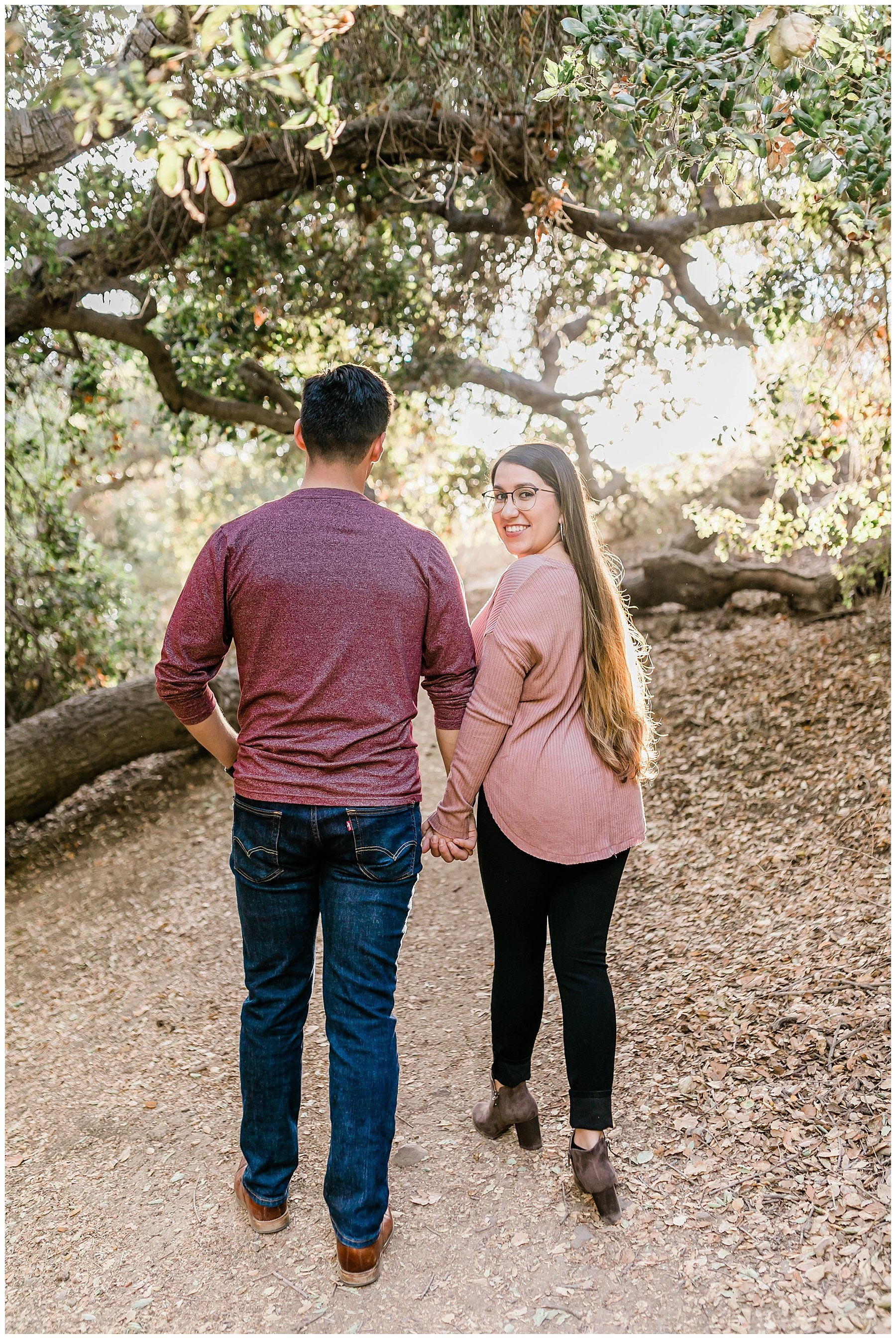  engaged couple walking through pathway hand in hand 