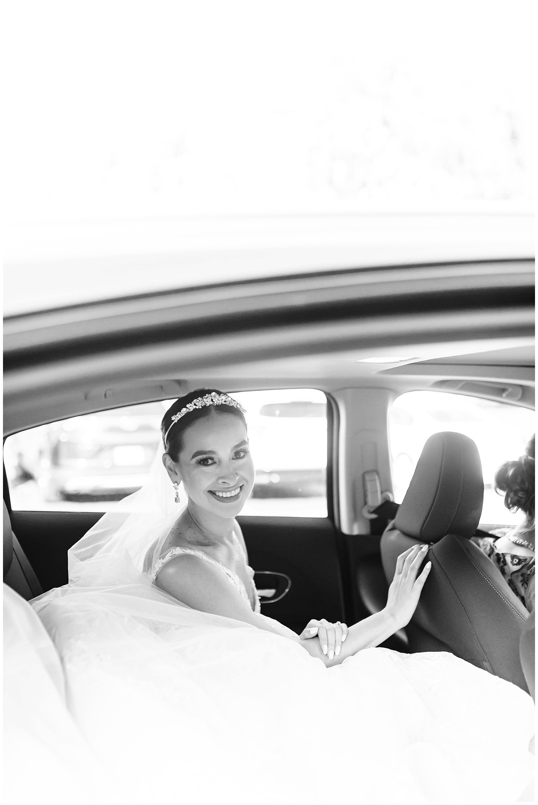  black and white photo of bride getting into the car 