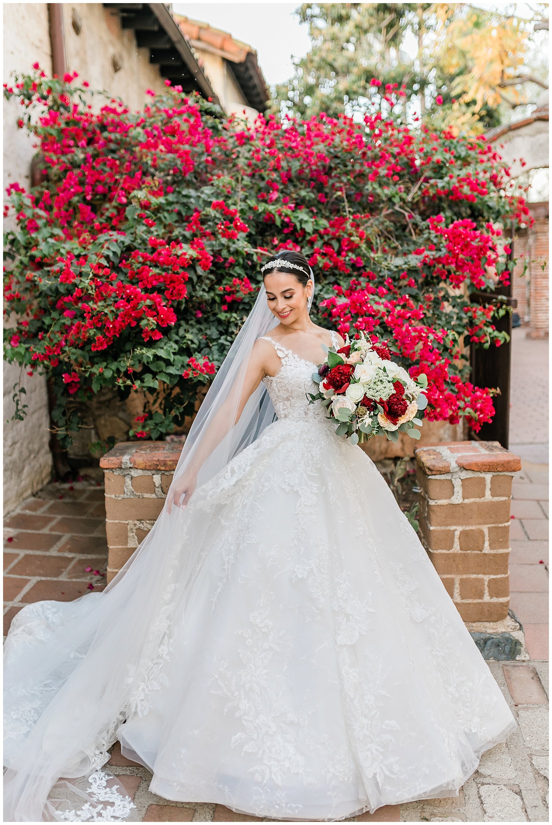  bride standing in front of red rose bush 