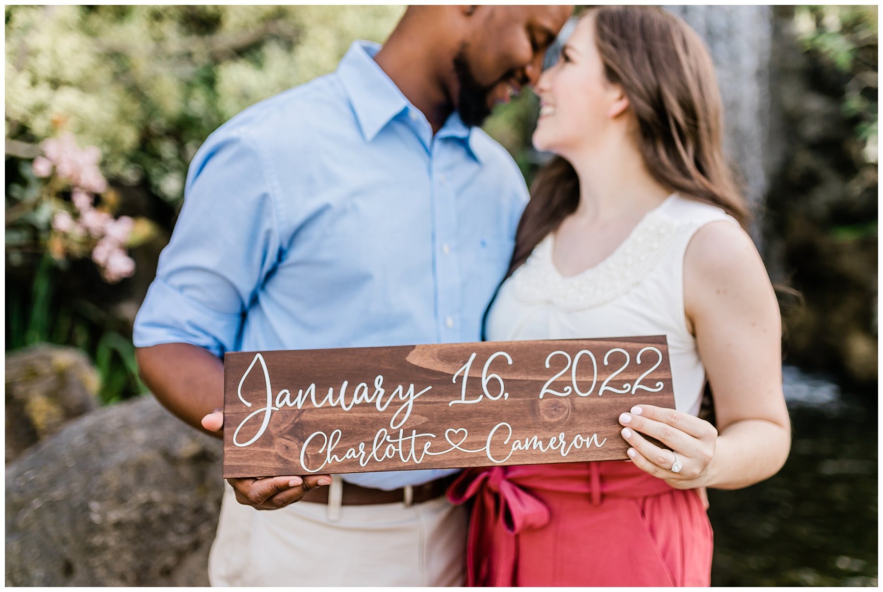  engaged couple holding a sign with their wedding date on it 