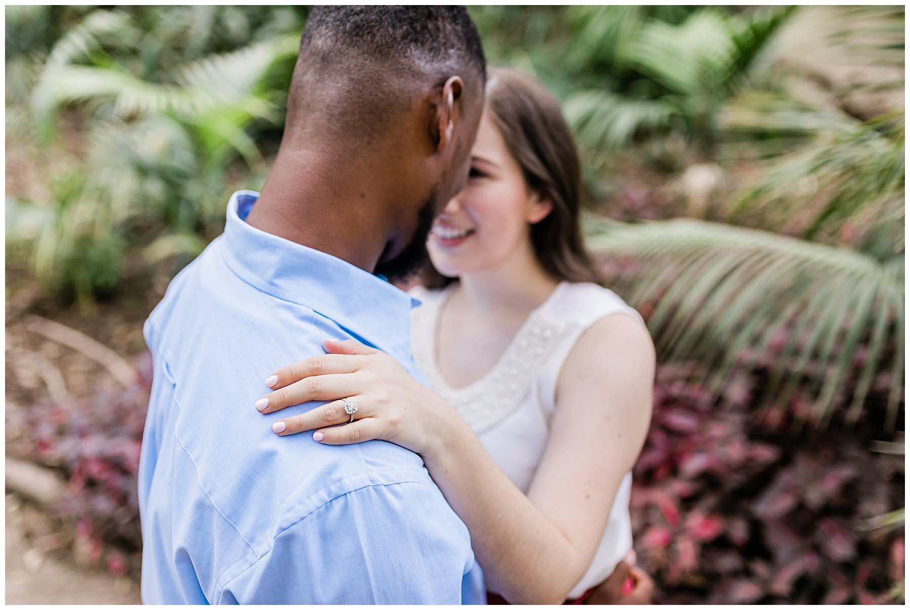  engaged couple in front of greenery 