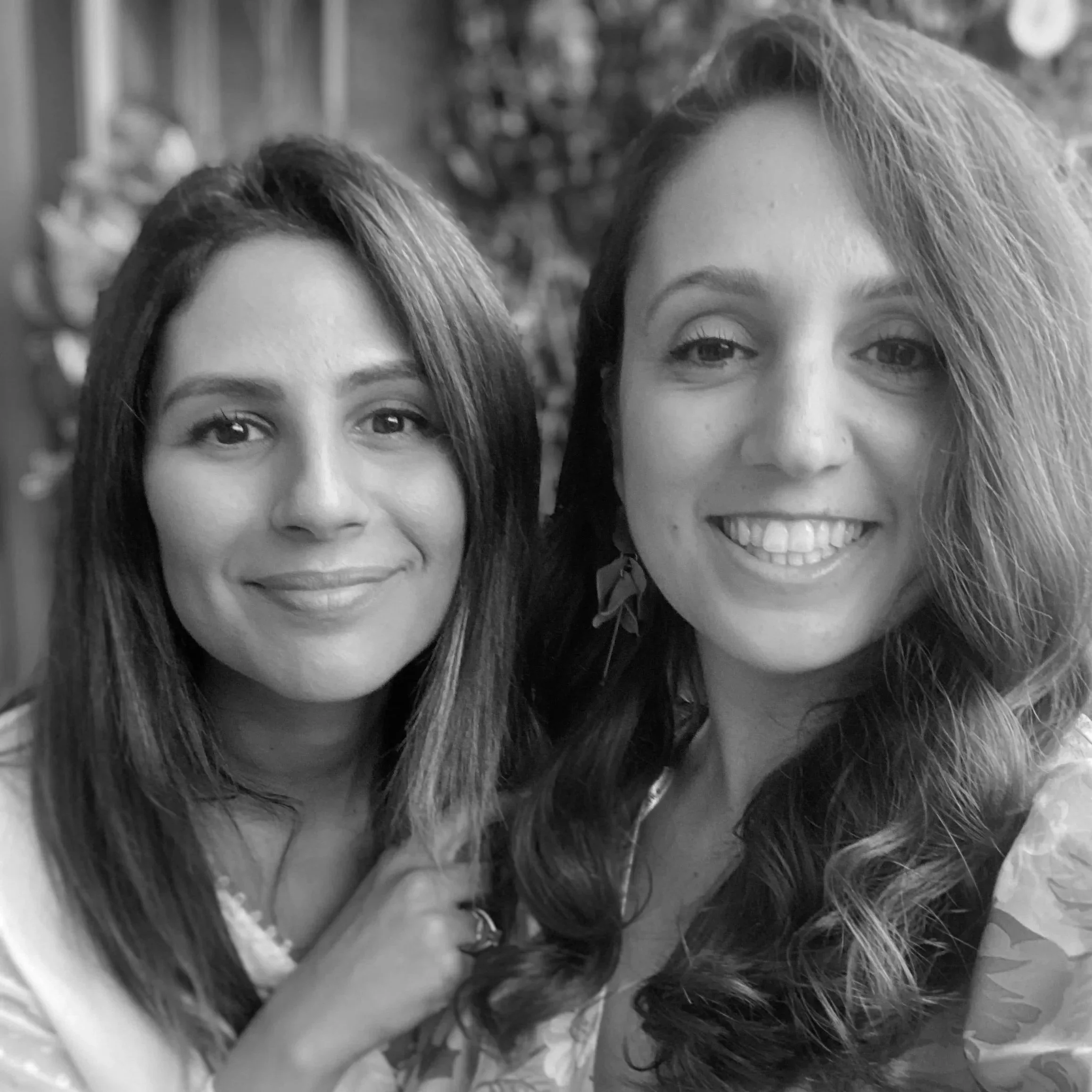 Black and white photo of two smiling women close together, outdoors.