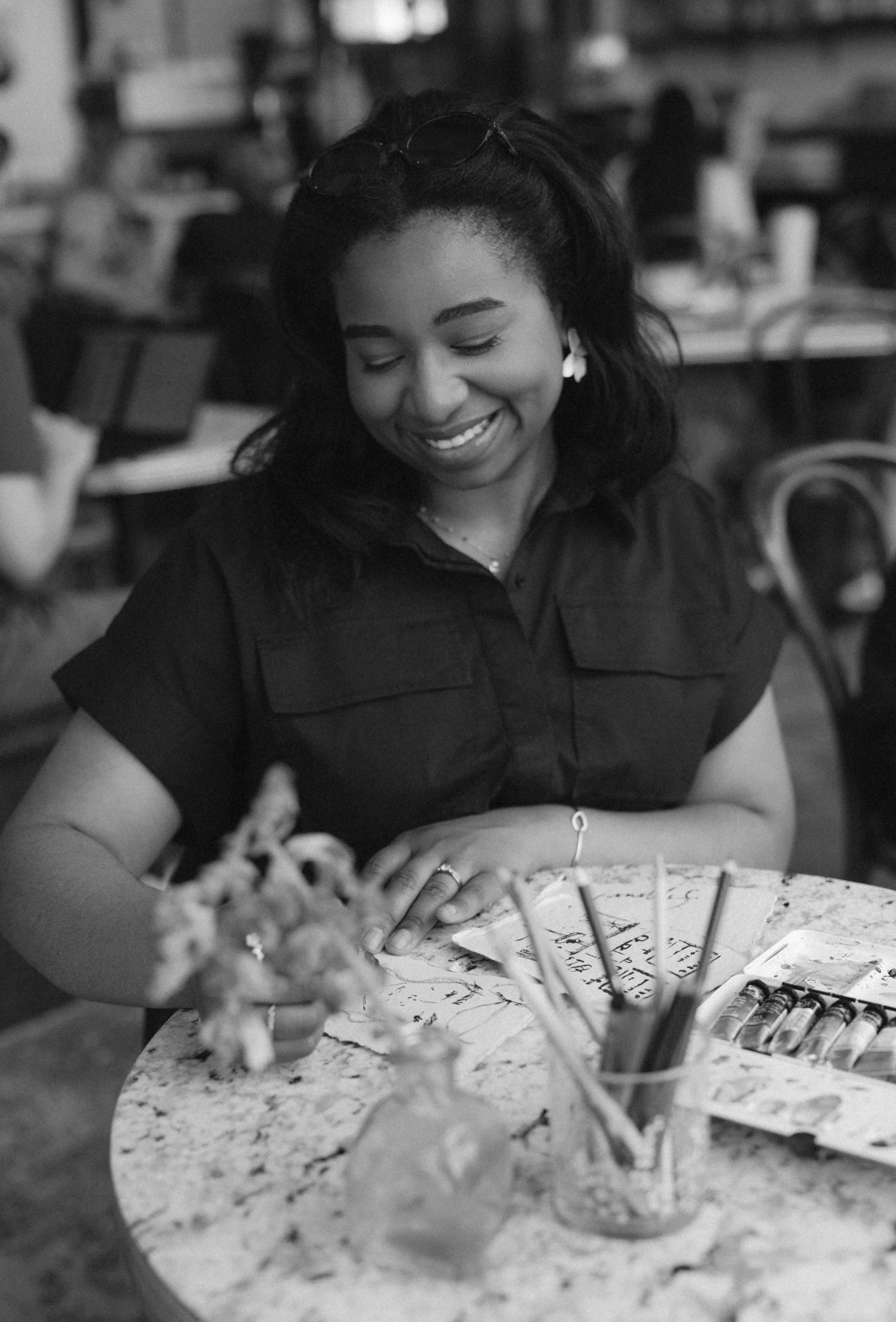 A woman smiling with her eyes closed, sitting at a table with birthday decorations and a birthday cake in front of her.