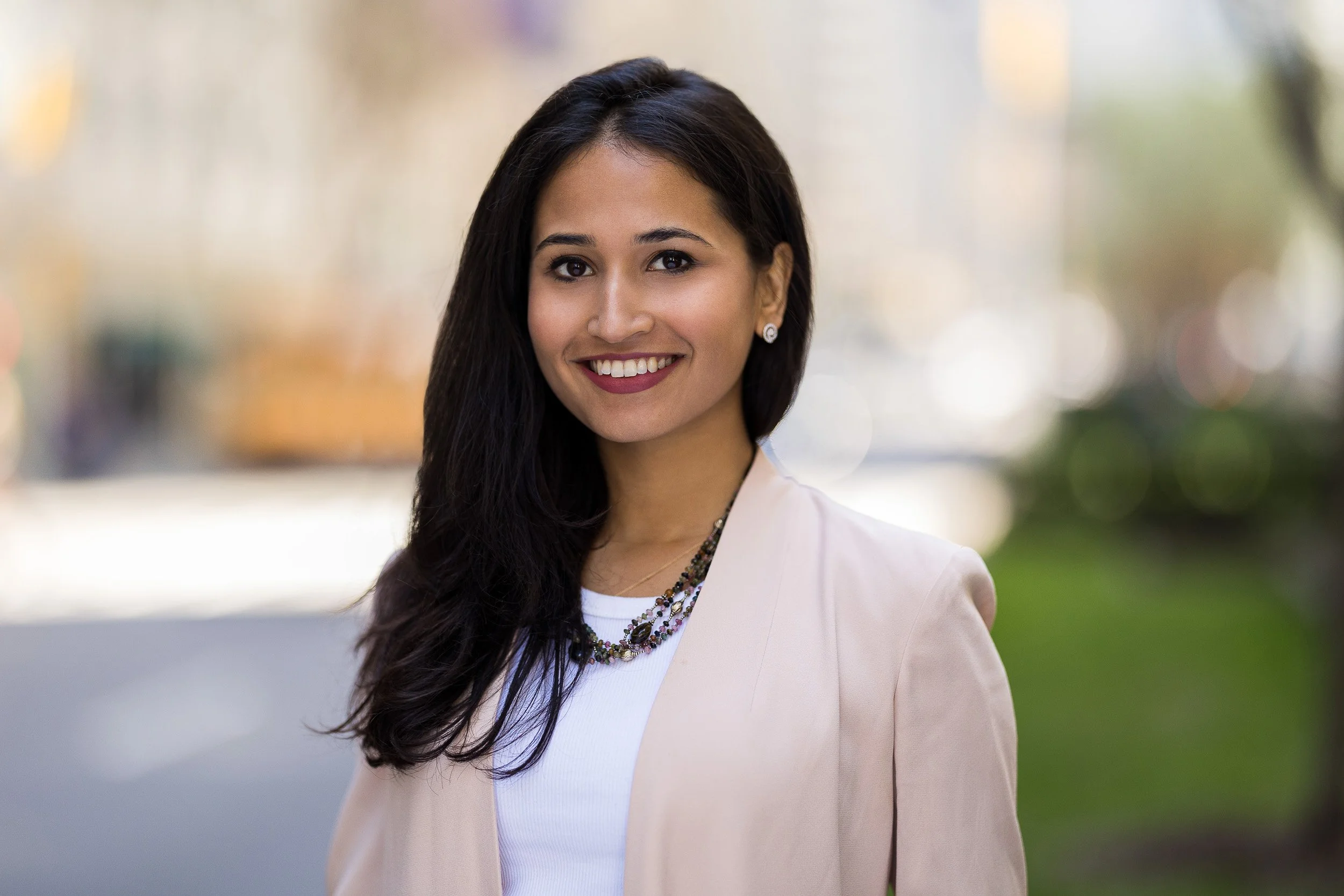 Modern female corporate headshot of a young woman smiling outdoors in NYC