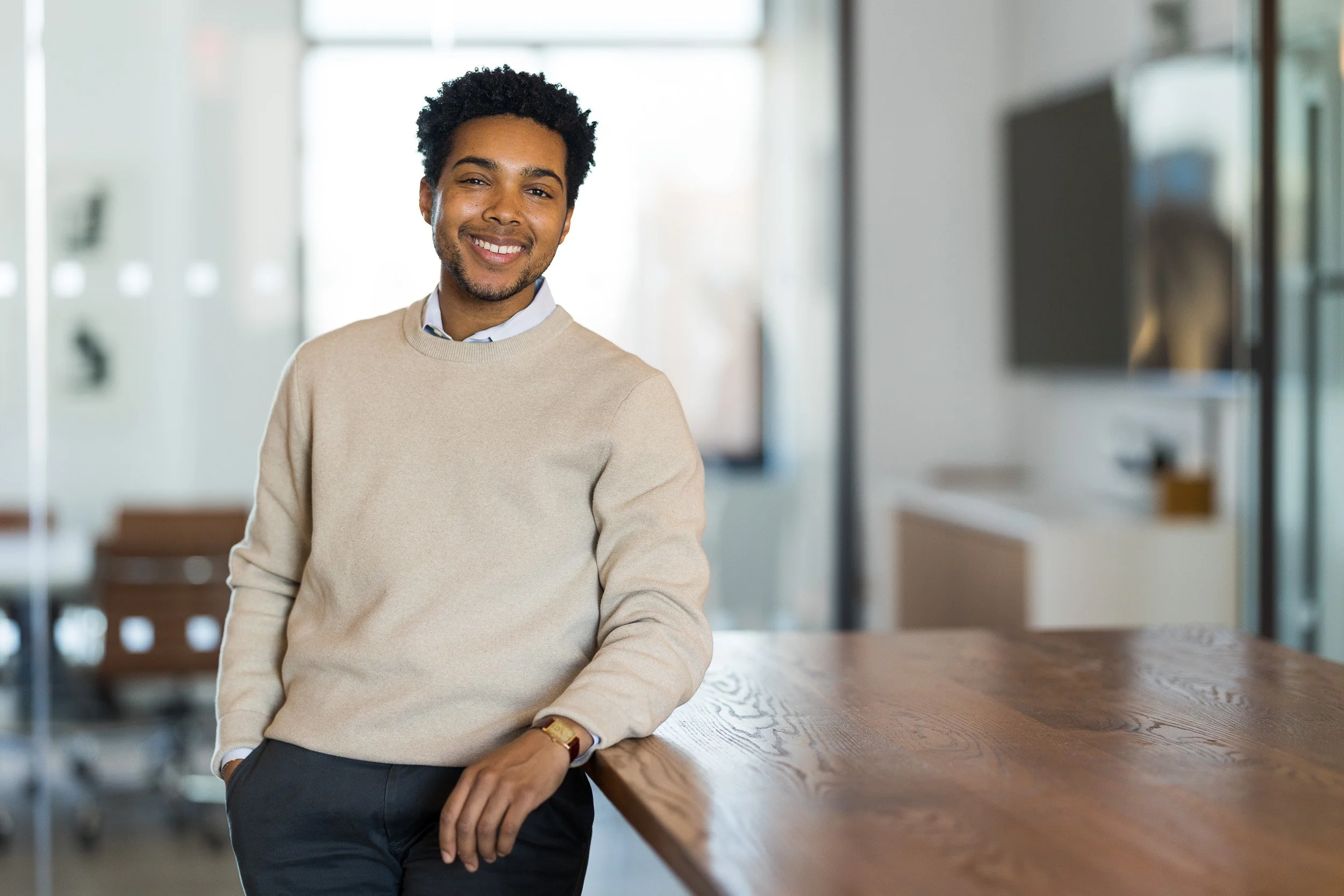 Creative corporate headshot of a man posed by a table in his NYC office