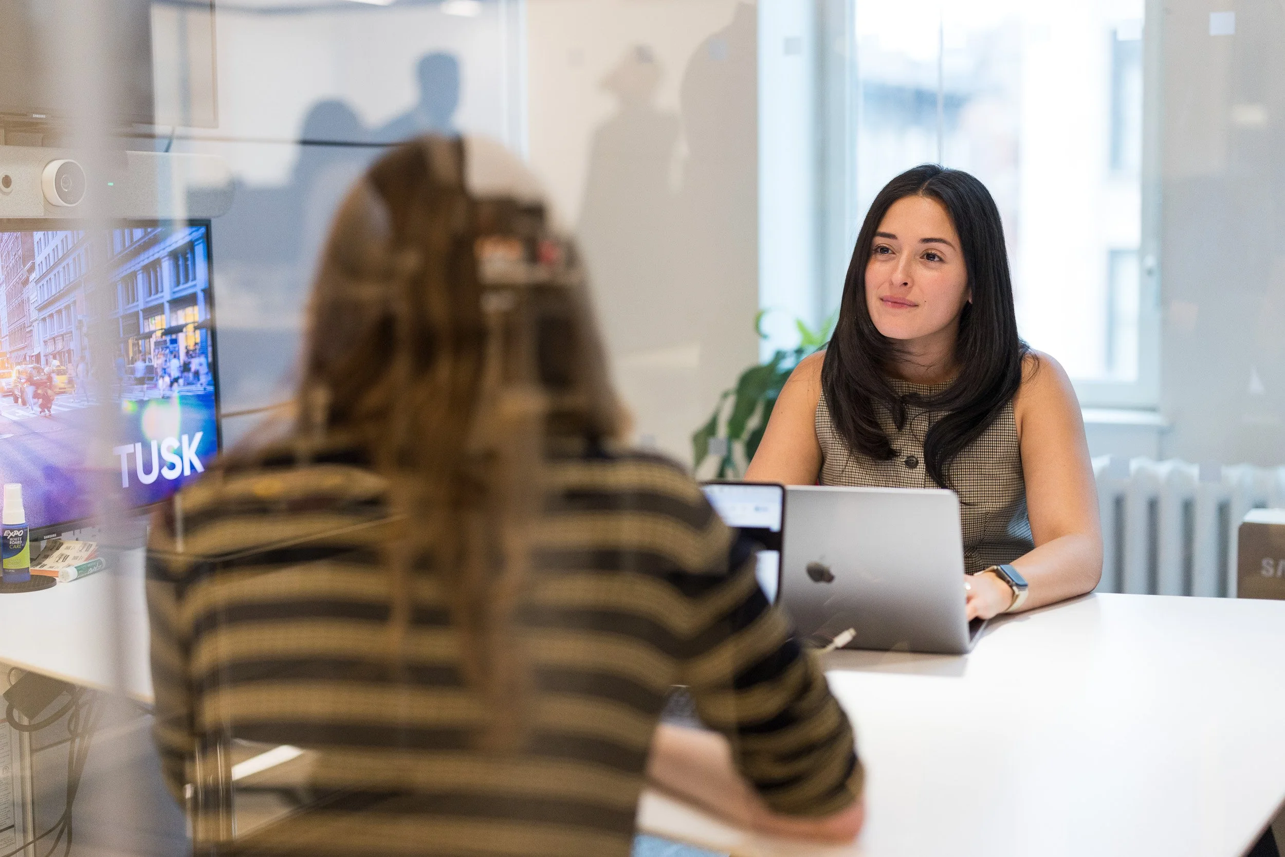 Corporate lifestyle photography of a young woman having a meeting with another employee in a small office. 