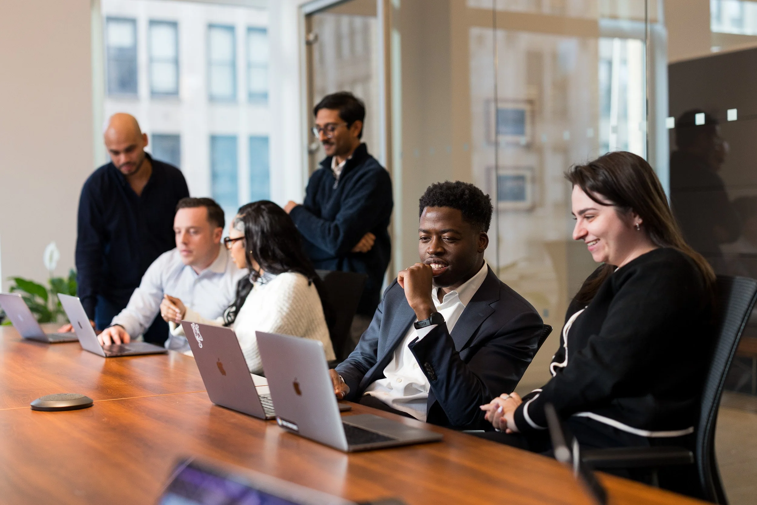 Corporate lifestyle photography of a group of employees coworking in a conference room, with the focus on a male looking at his laptop. 