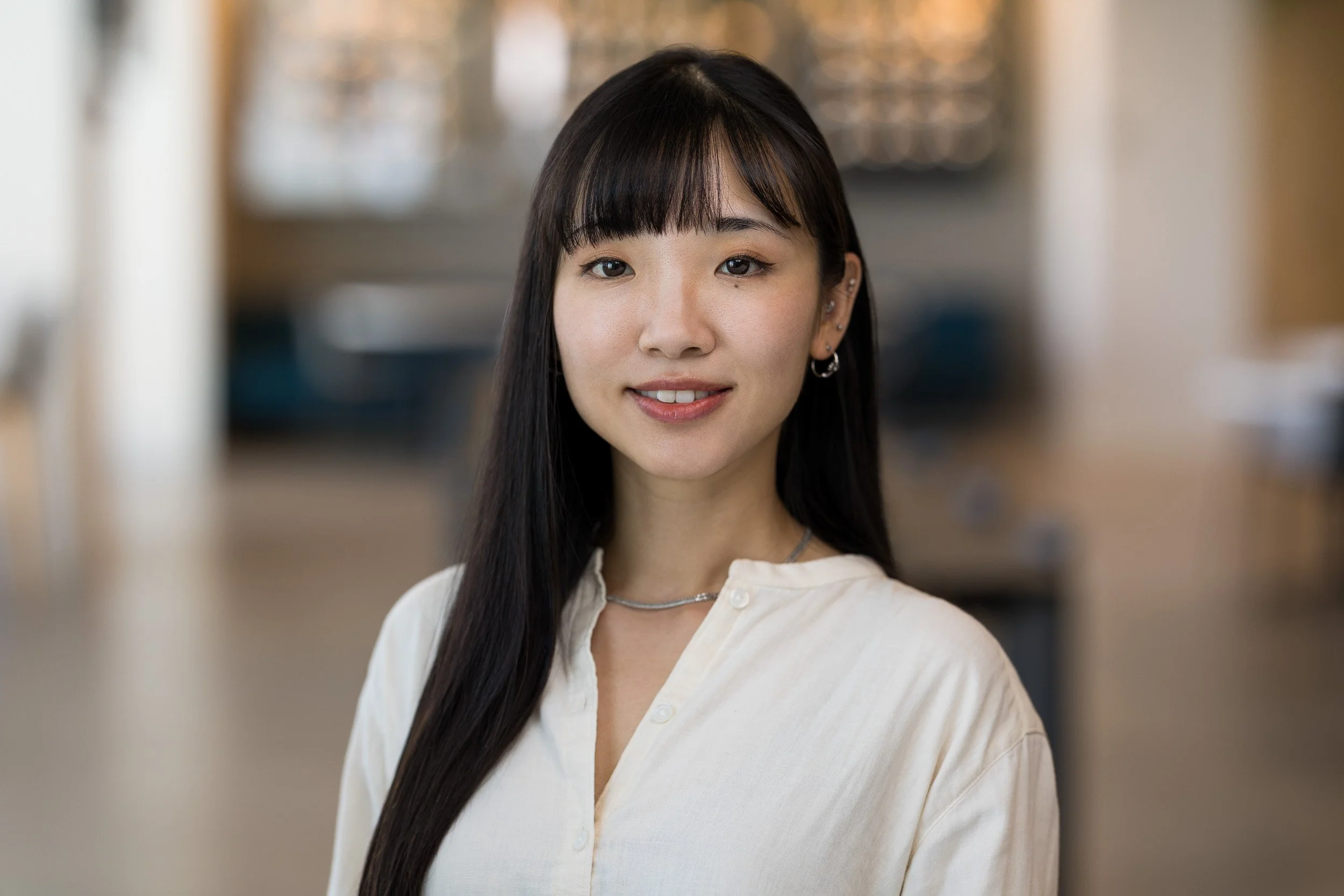 Modern corporate headshot of a young Asian female smiling in her office in NYC