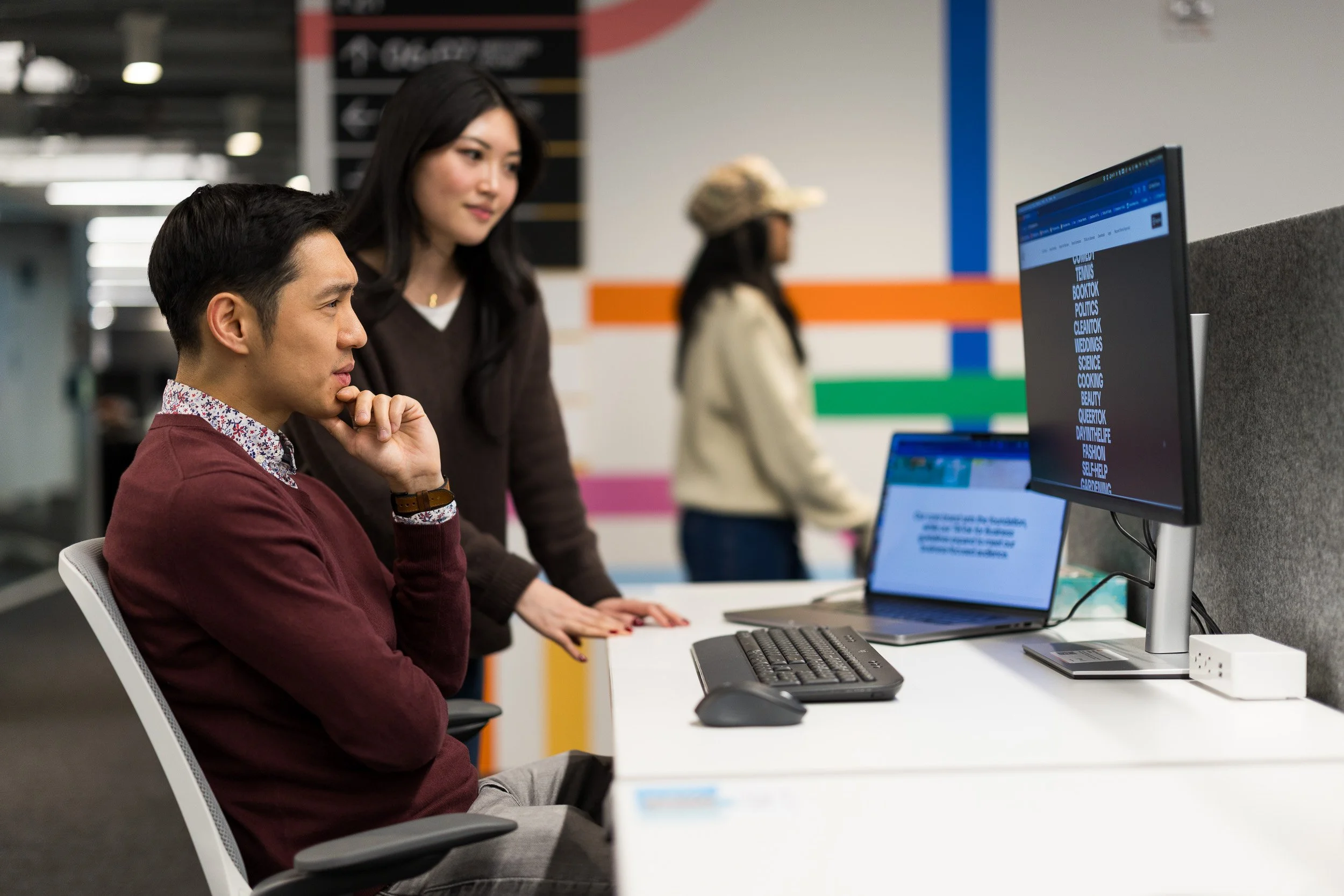 Young Asian male and female coworking at a computer desk in an office