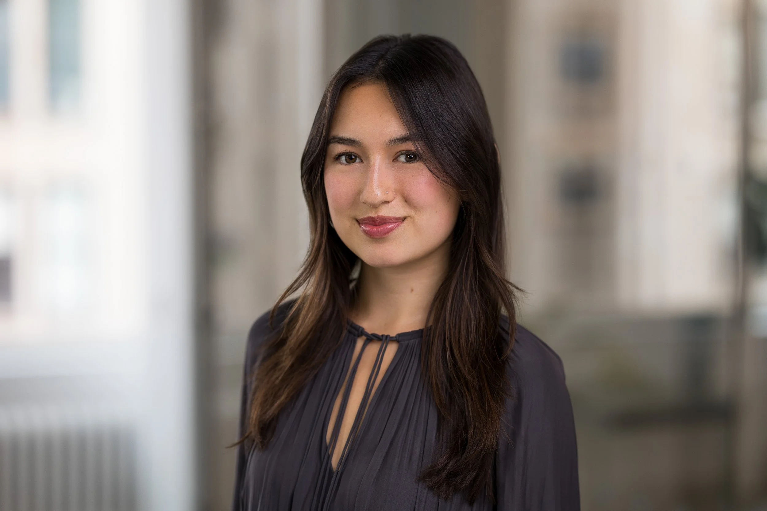 Female professional headshot of a young woman smiling with a blurred office background