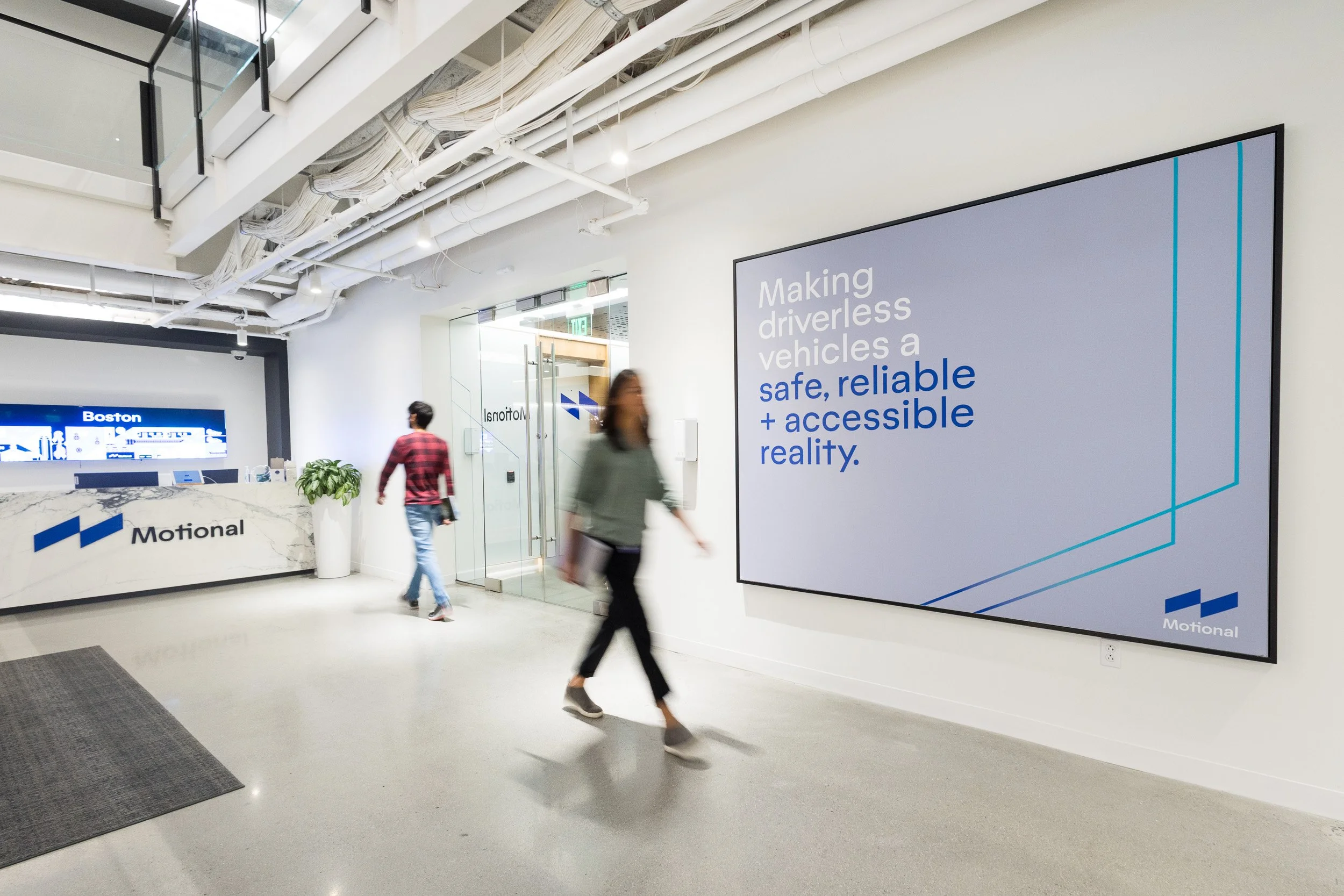 Two people walking through an office with company branding visible throughout the scene. 
