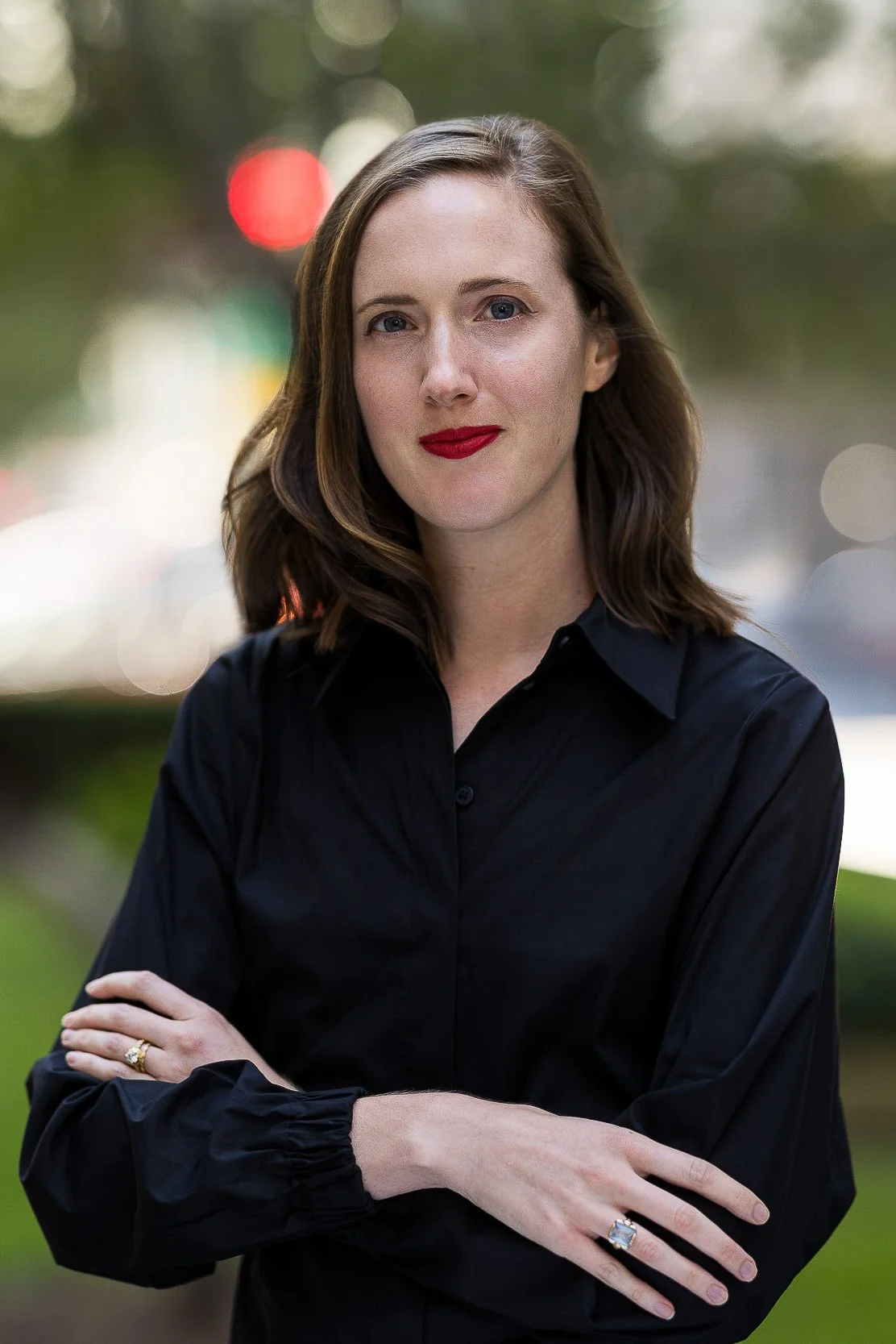 Corporate headshot of a white woman wearing a black blouse with arms crossed outdoors in NYC