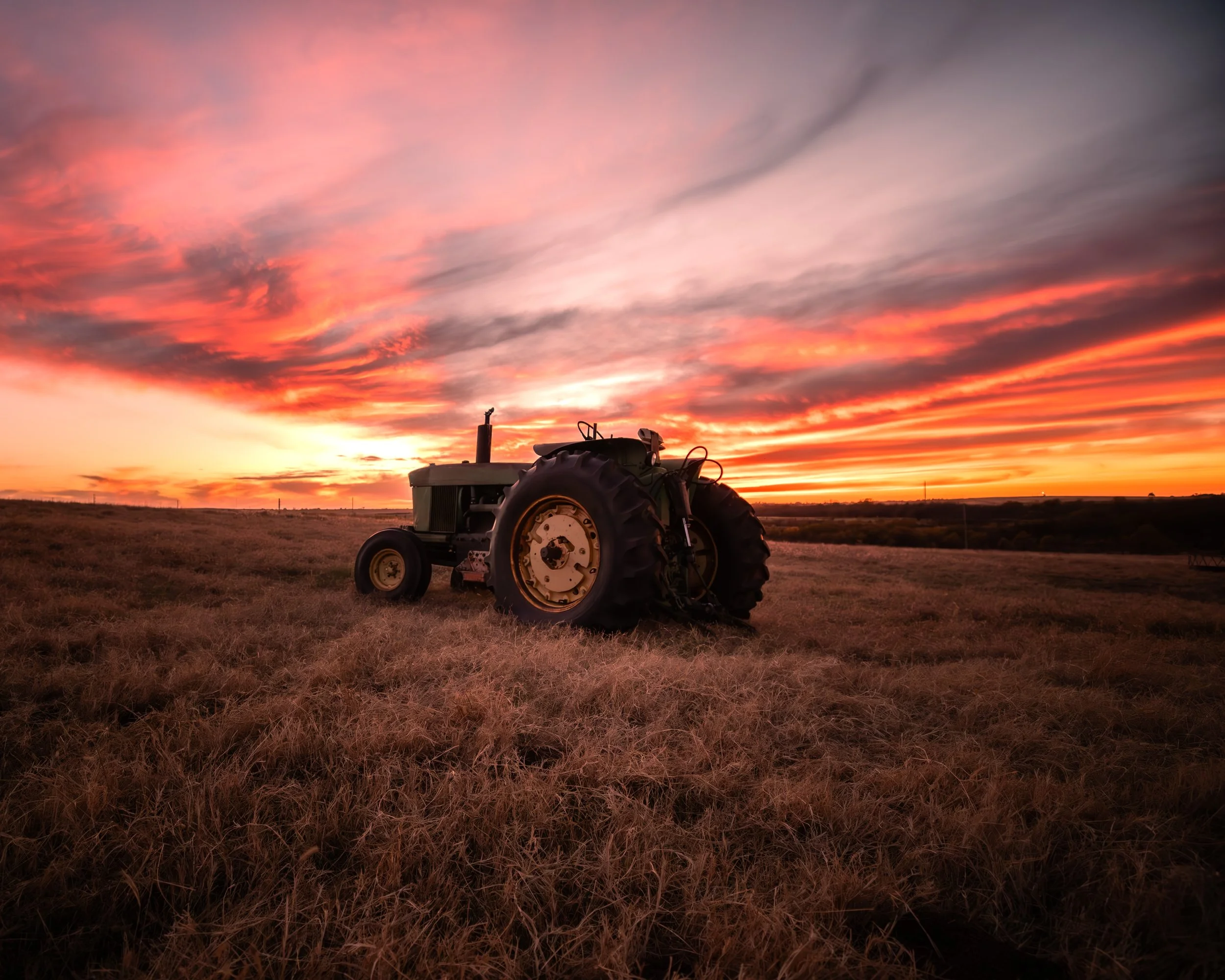 Historic tractor in an Oklahoma pasture beneath a colorful sunset, capturing rural Oklahoma, agriculture, farm life, ranching, prairie landscapes, western heritage, and country living.