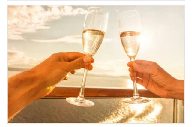 Couple raising Champagne glasses during a sunset celebration on the water.
