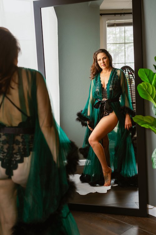 Woman in elegant lingerie and robe standing in front of mirror