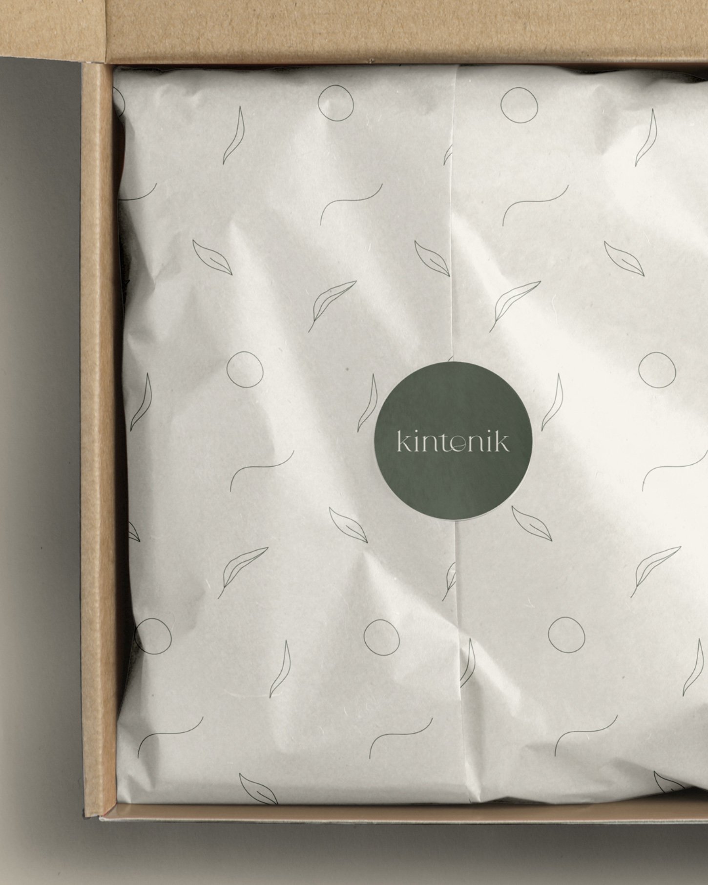 Kintonik brand packaging featuring tissue paper with leaf and circle design and green logo sticker
