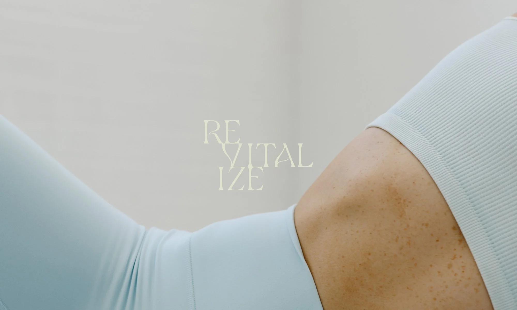 Close-up of a person's shoulder and upper arm wearing light blue athletic clothing, with text 'REVITALIZE' in the background.