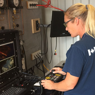 Woman operating a remote control in a technical environment with electronic equipment and monitors
