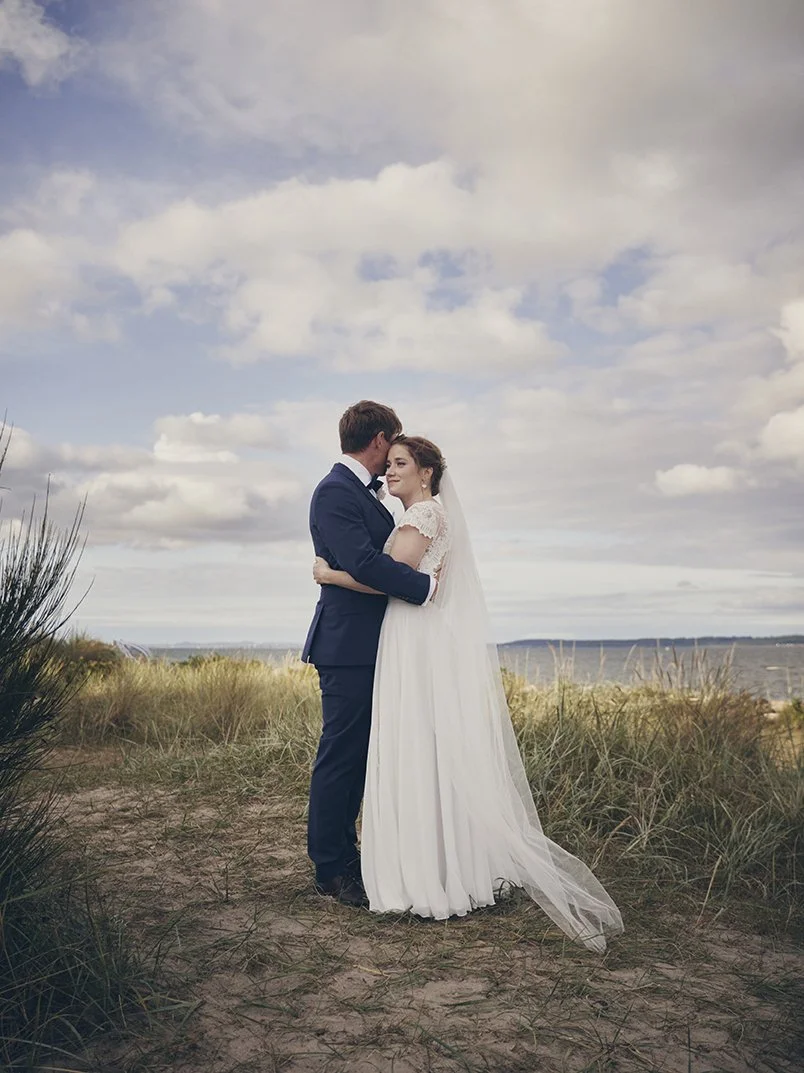 Brudepar ved strand med hav i baggrunden – bryllup i Danmark