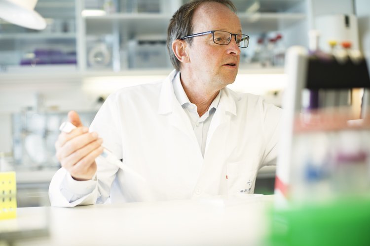 Scientist in a lab coat working with a pipette in a laboratory.