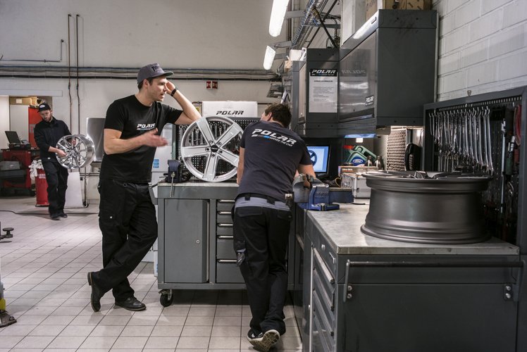 Workers in an automotive workshop with Polar equipment and wheel rims.