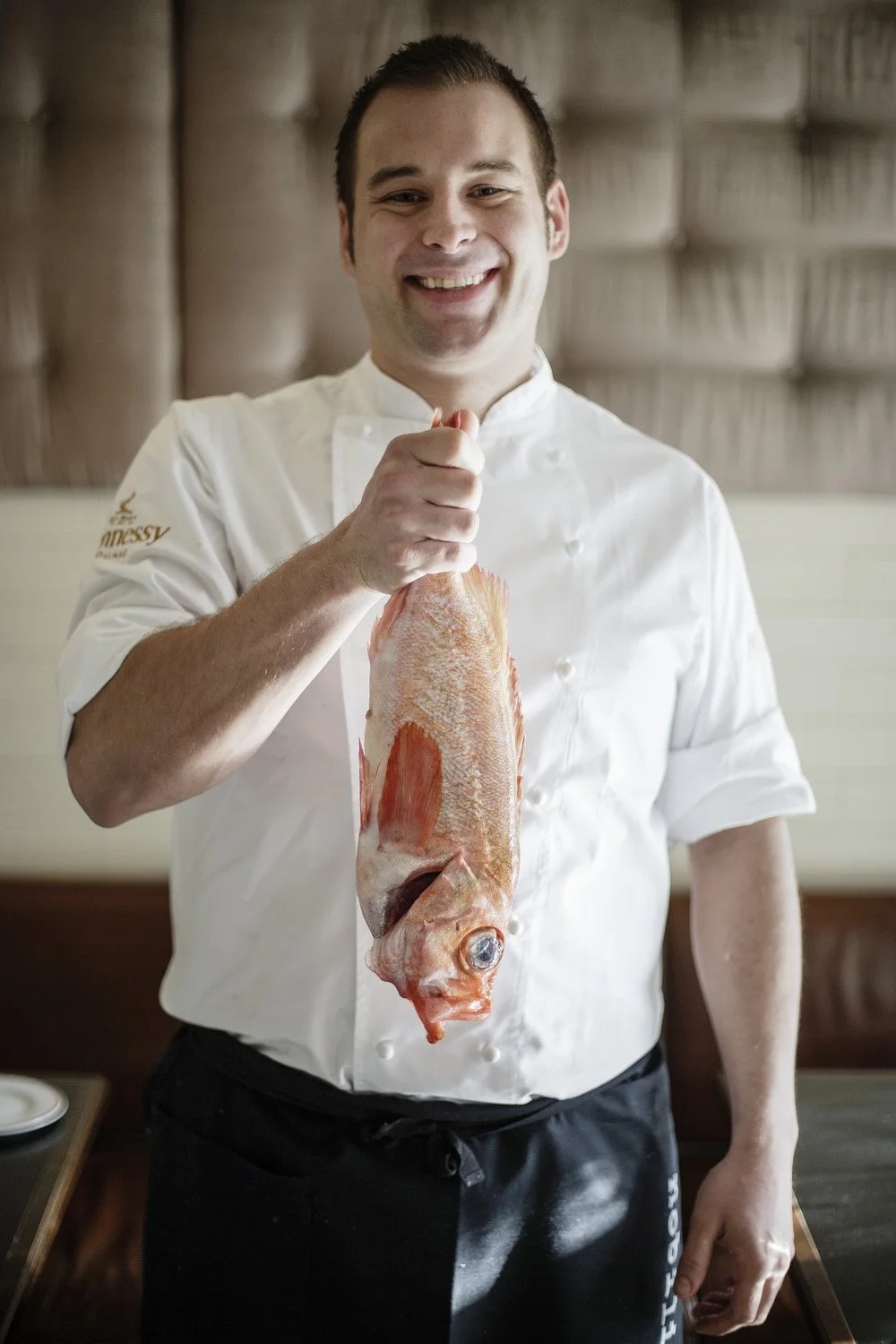 Kokk med fersk fisk poserer i restauranten