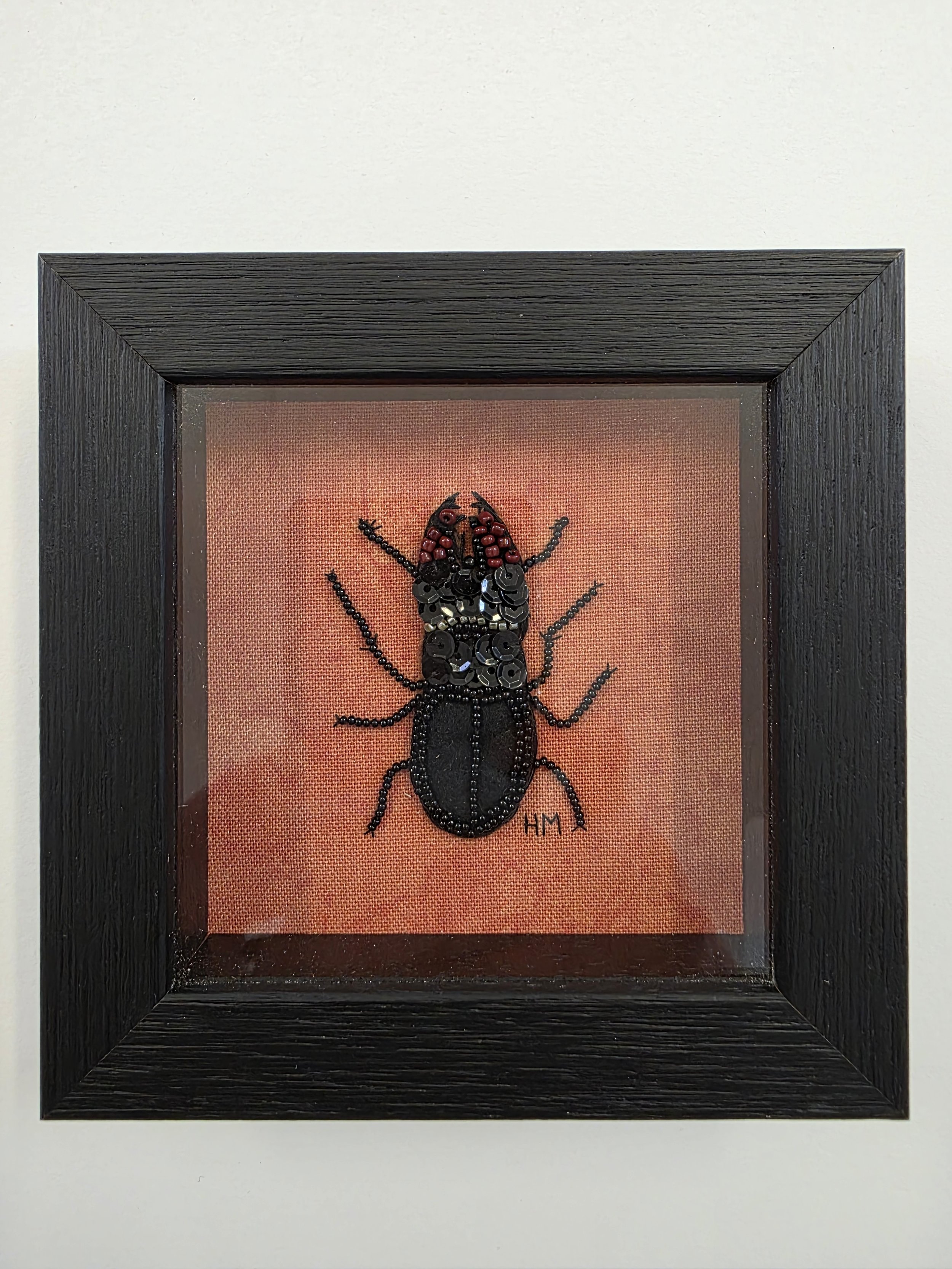 Hand-embroidered Stag Beetle with beadwork and sequins, displayed in a deep black box frame with raised glass.