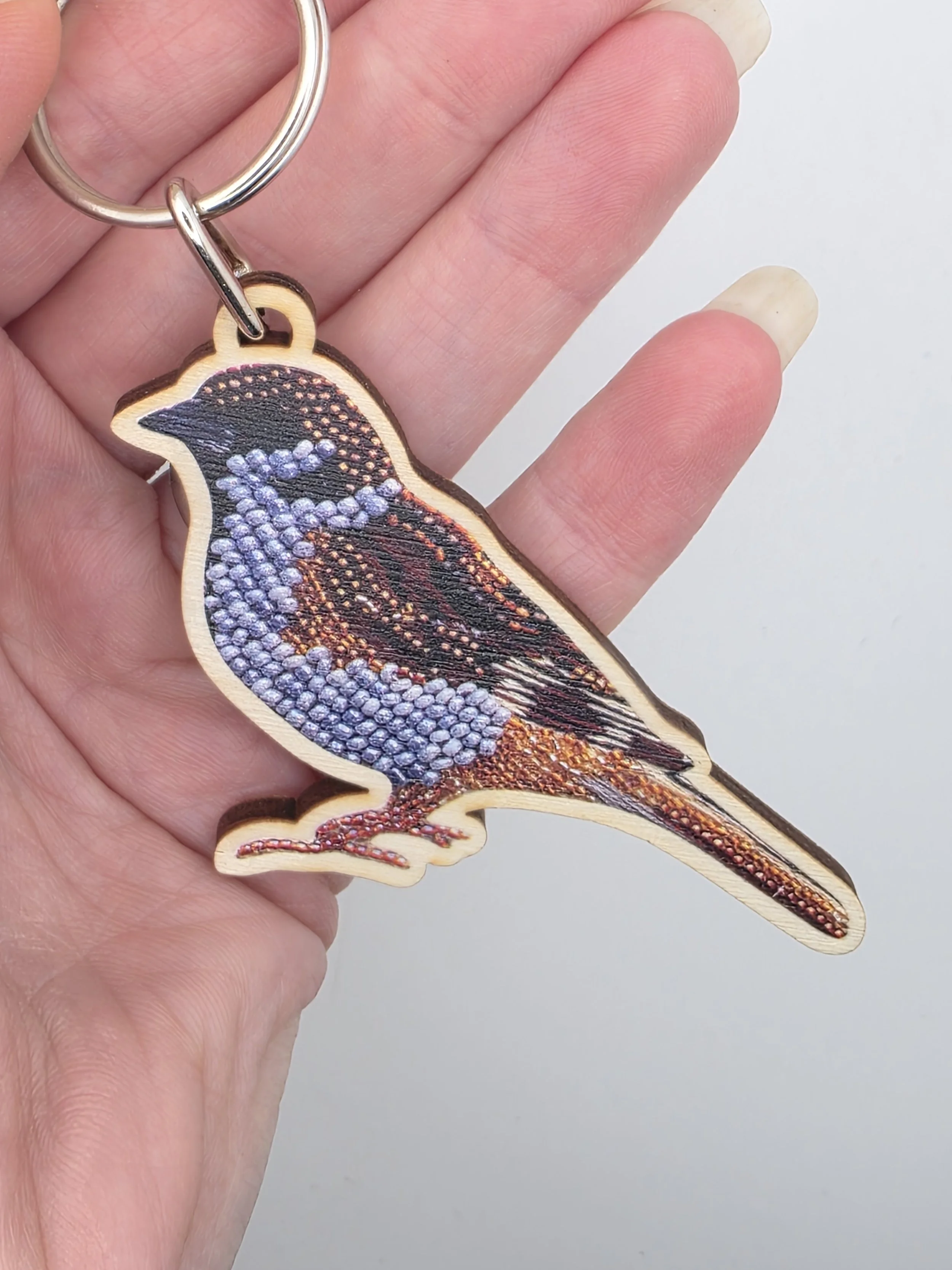 Close-up of Eurasian Tree Sparrow keyring showing bead embroidery detail and printed wood texture