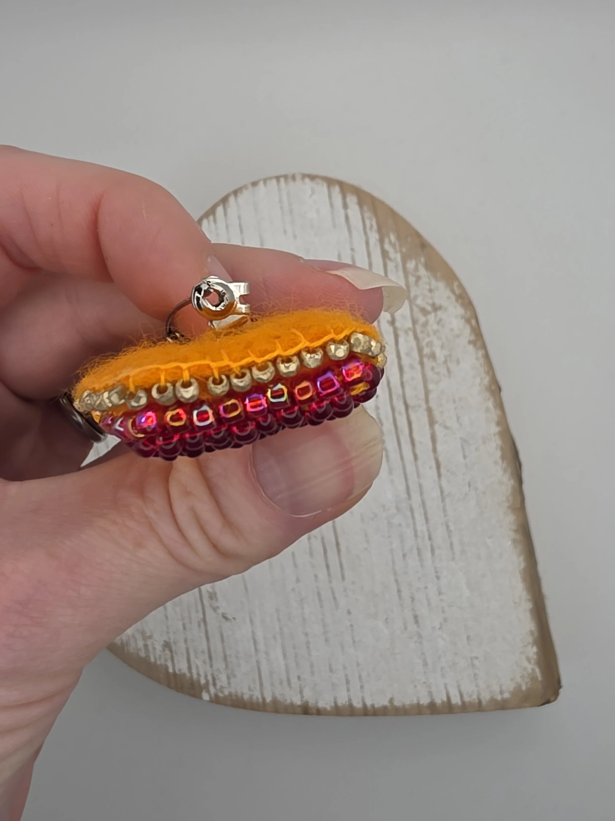 Side view close-up of gold beaded blanket stitch edging on handmade ice lolly brooch. Highlights craftsmanship and texture.
