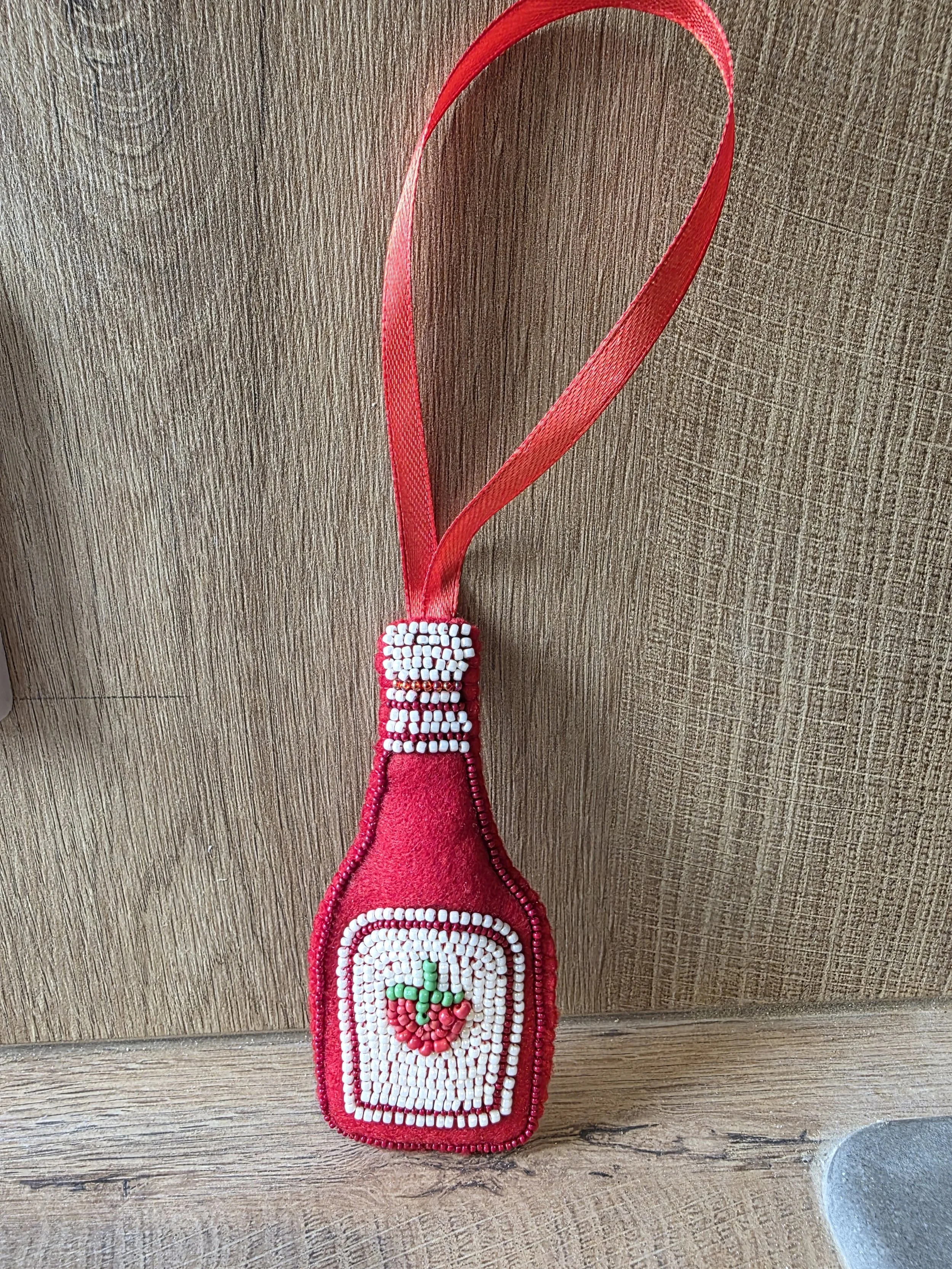 Handmade beaded tomato sauce Christmas decoration leaning against a wooden background