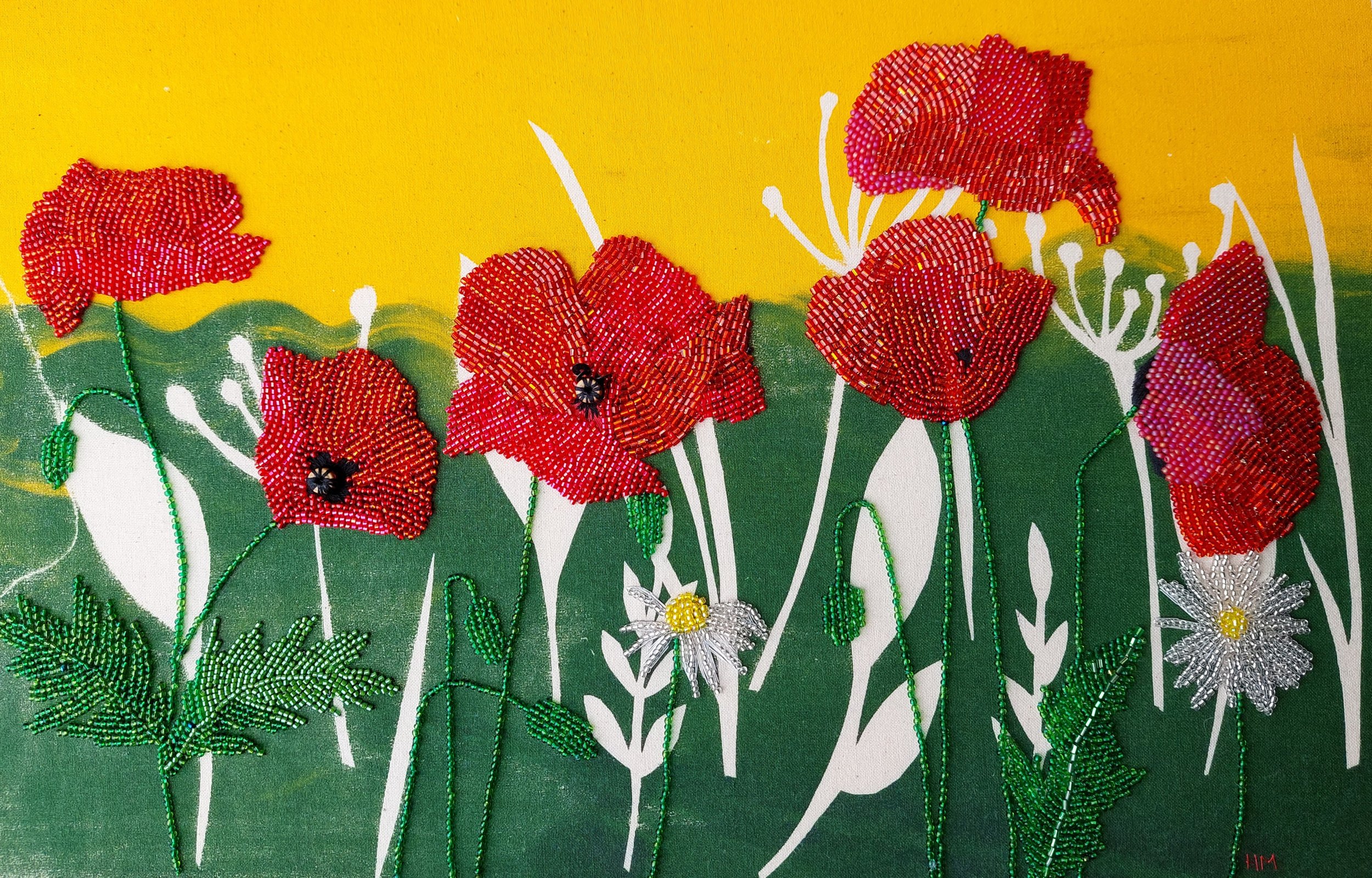 Close-up of original mixed media textile artwork showing hand-sewn beaded poppies and daisies on screen printed fabric with golden sky and green grass.