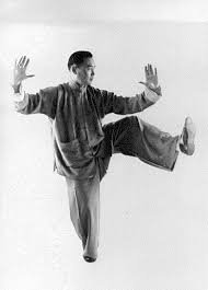 A person practicing martial arts or a similar activity, standing on one leg with arms raised and the other leg lifted