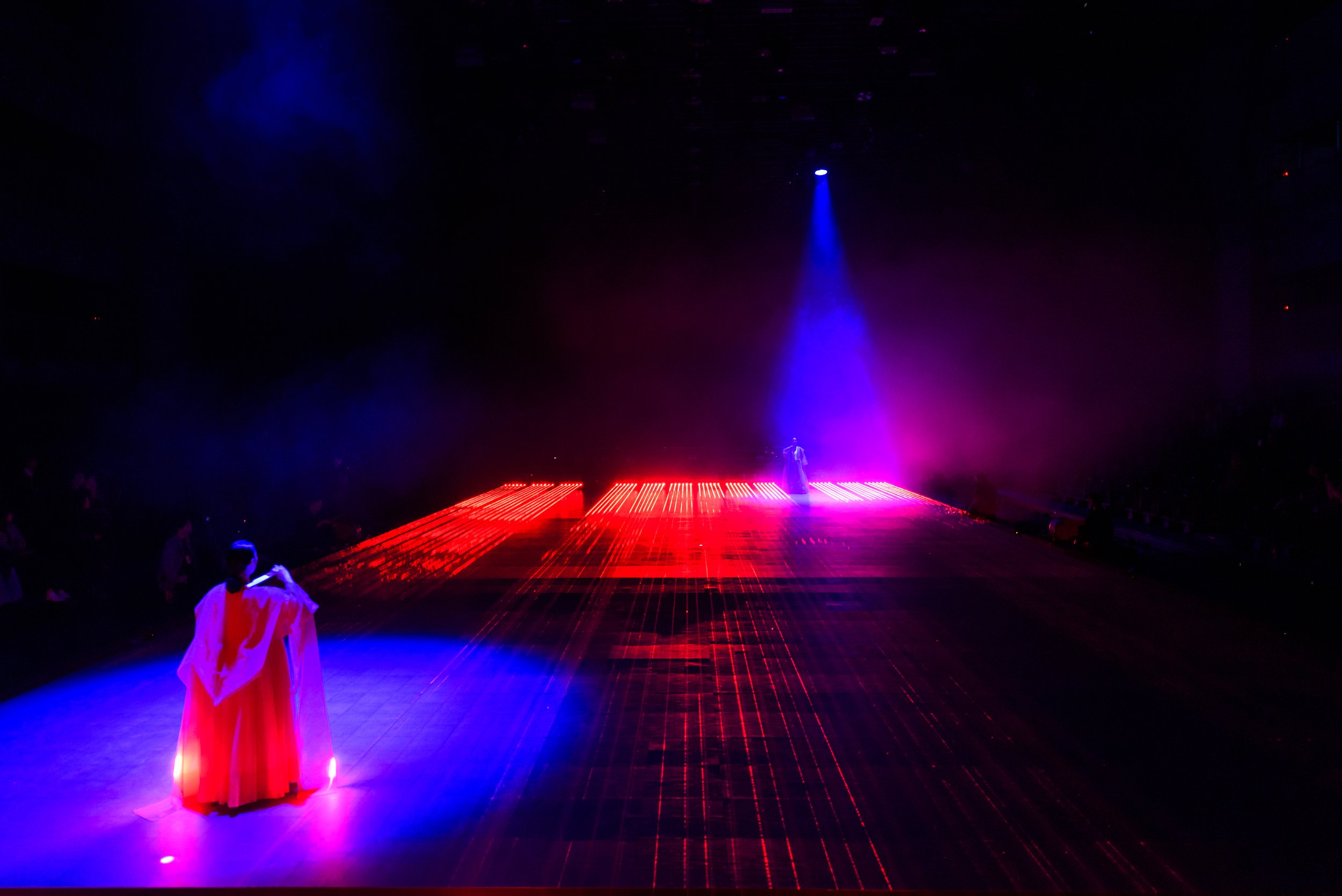 People on stage with dramatic lighting in red and blue hues.